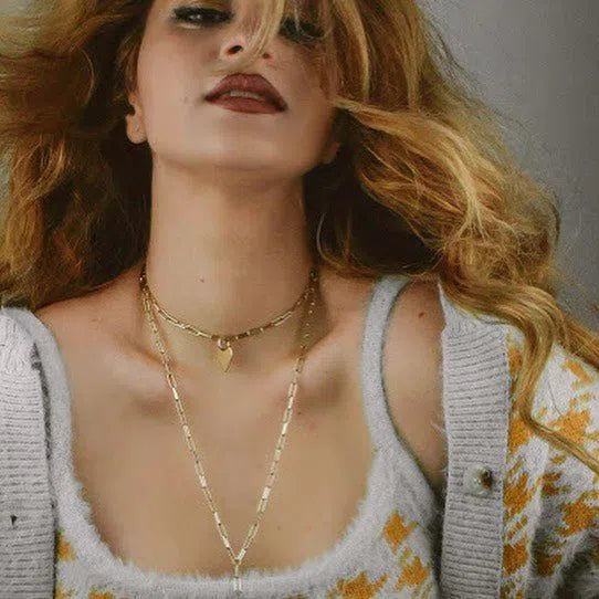 Woman showcasing layered gold necklaces and signature jewelry for 2021 outfits
