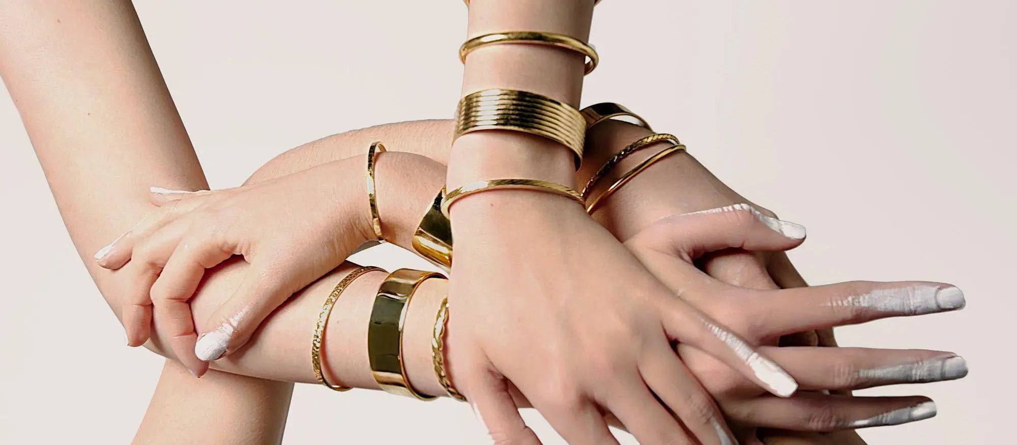 Stacked gold bracelets on hands from the Cuffs jewelry collection