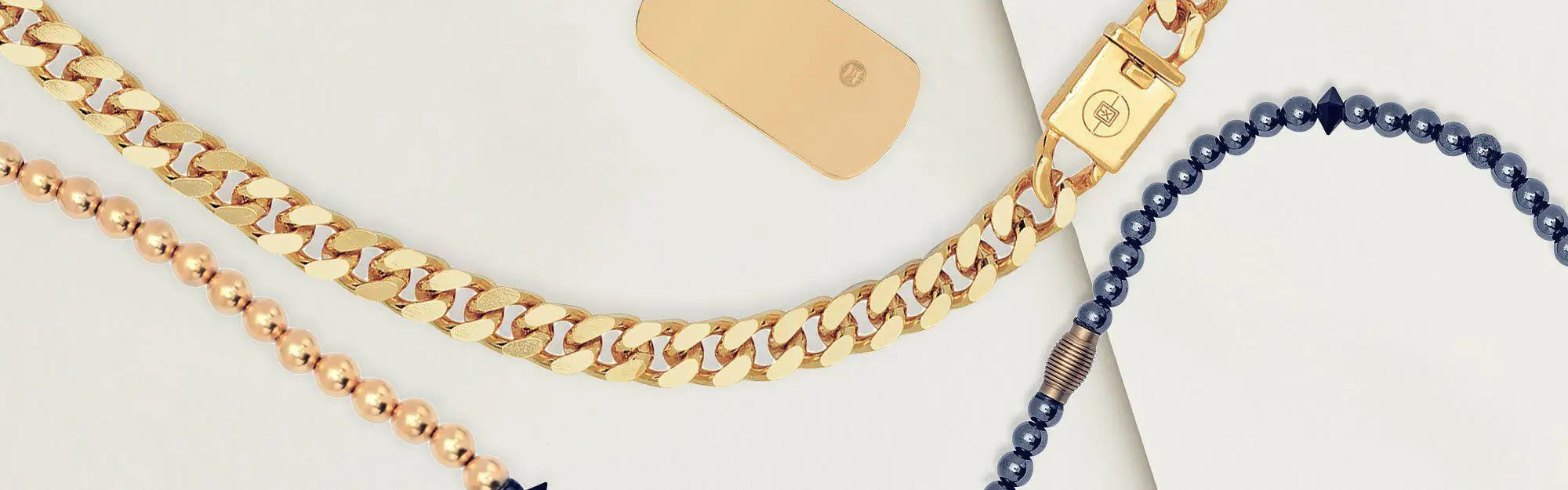 Men’s necklaces collection featuring a thick gold chain, a beaded gold chain, and a dark beaded necklace with a barrel-shaped bead