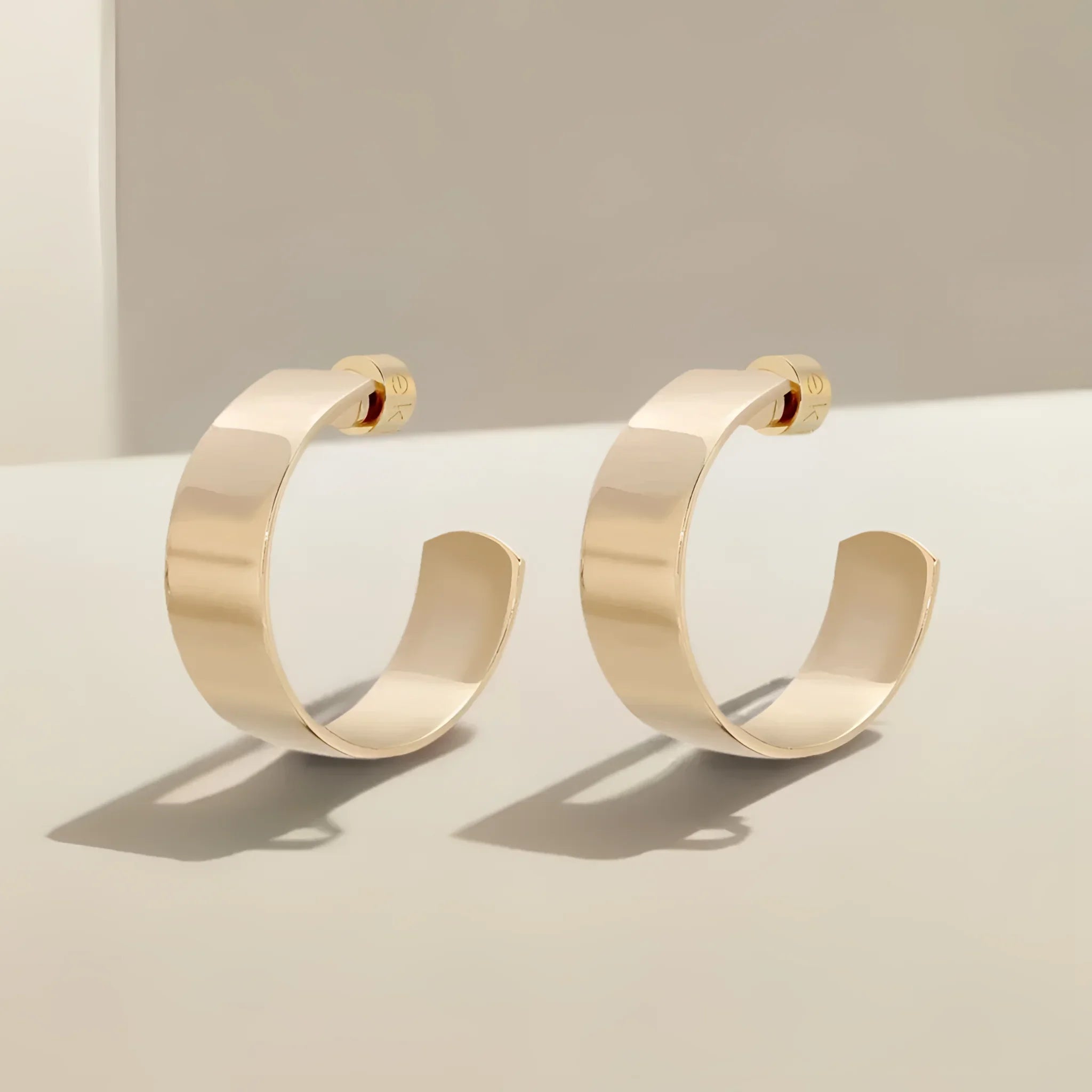 A pair of shiny gold Skylar Hoops earrings looking chic and stylish
