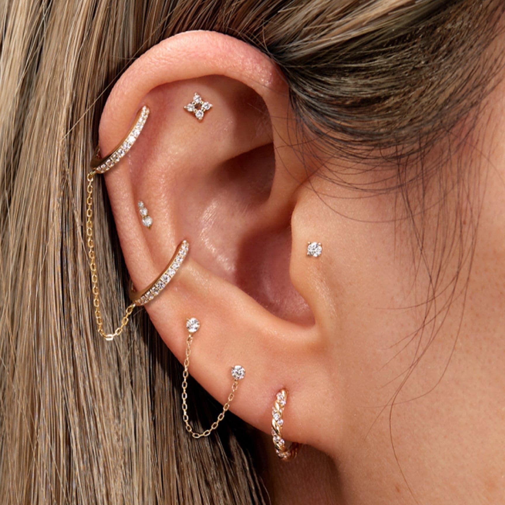 Ear with multiple gold and diamond piercings wearing 14K Gold & Diamond Twisted Huggie Hoops
