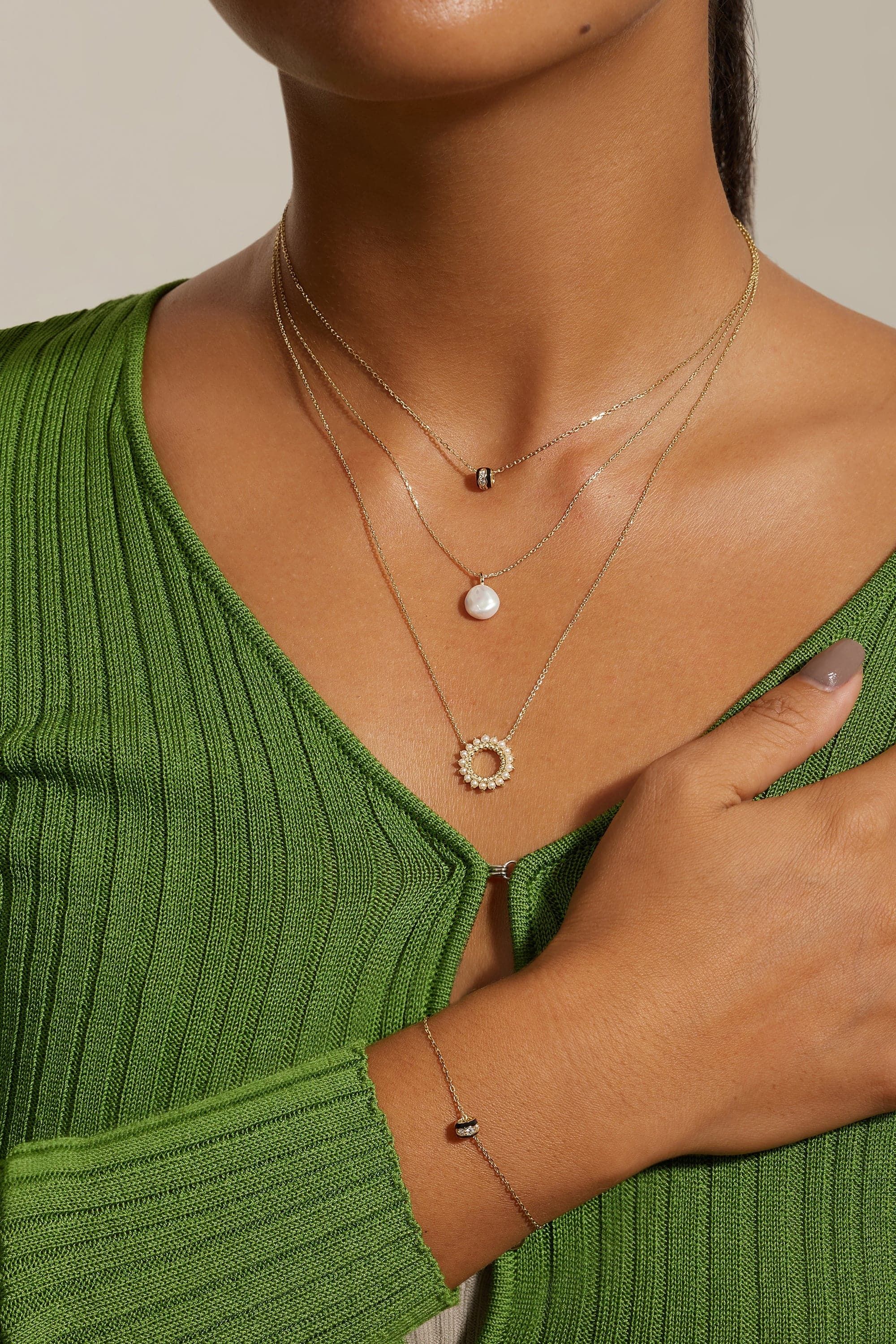 Woman wearing layered gold necklaces and a matching bracelet with Black Enamel CZ Channel Rondelle Necklace