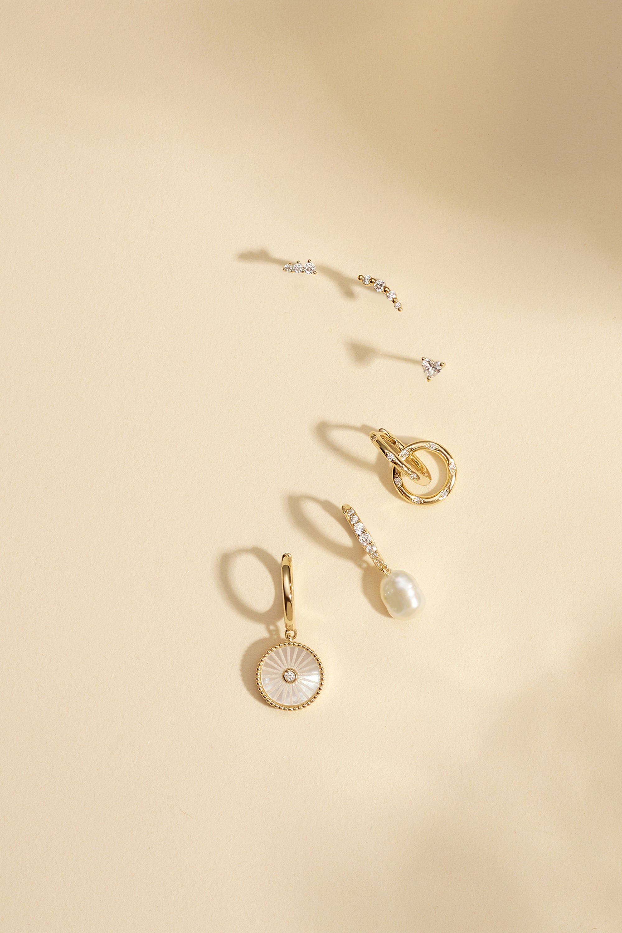 Assorted earrings featuring CZ Huggie Hoops with Circle Drop design