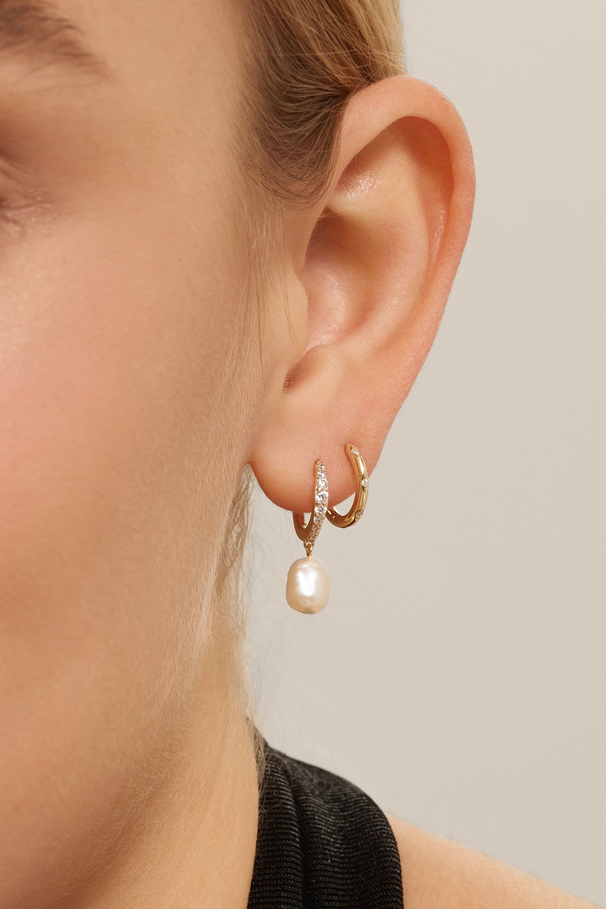 Ear with two gold hoop earrings from CZ Huggie Hoops With Pearl Drop jewelry set