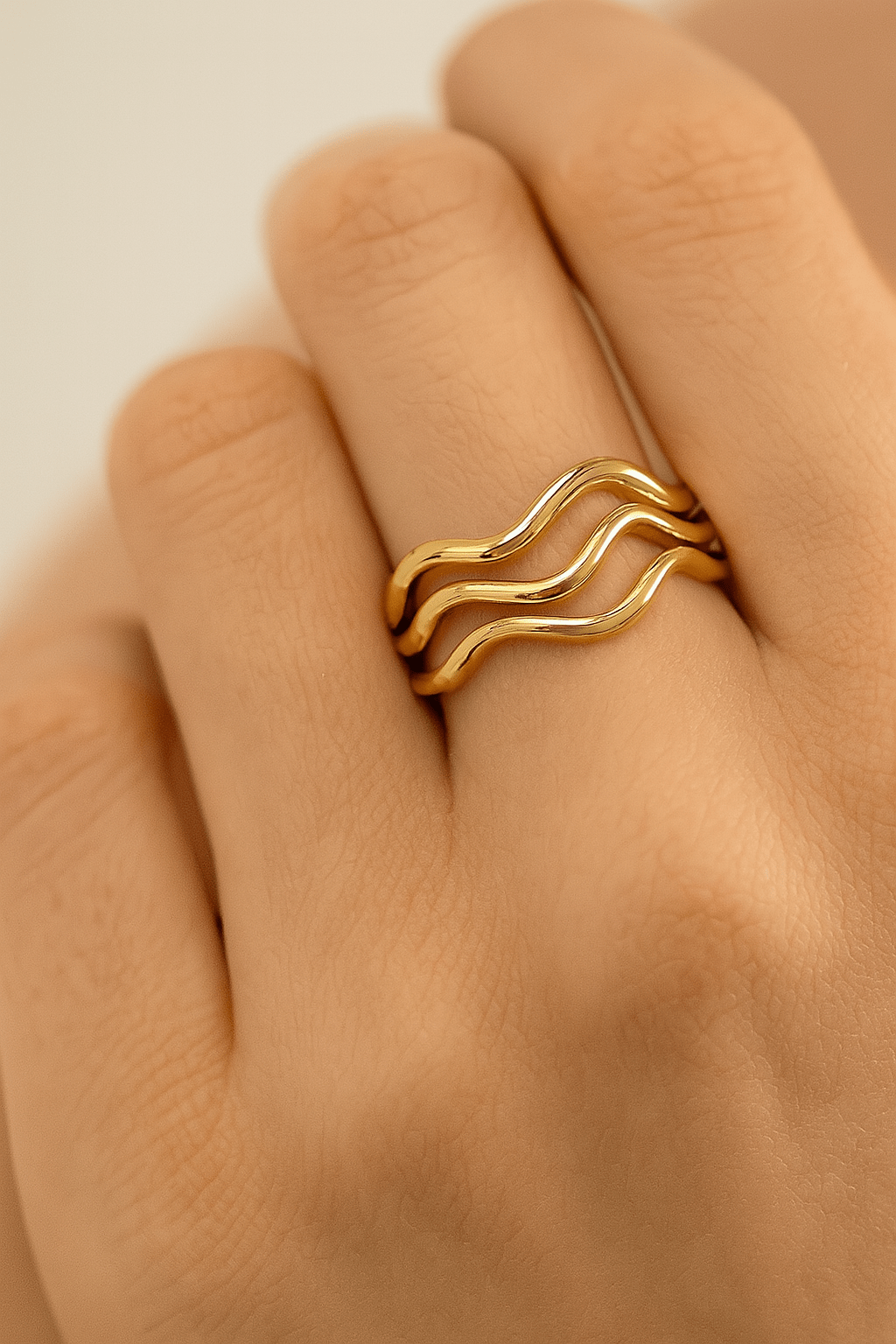 Three wavy gold rings on a finger showcasing the Super Thin Wavy Ring design