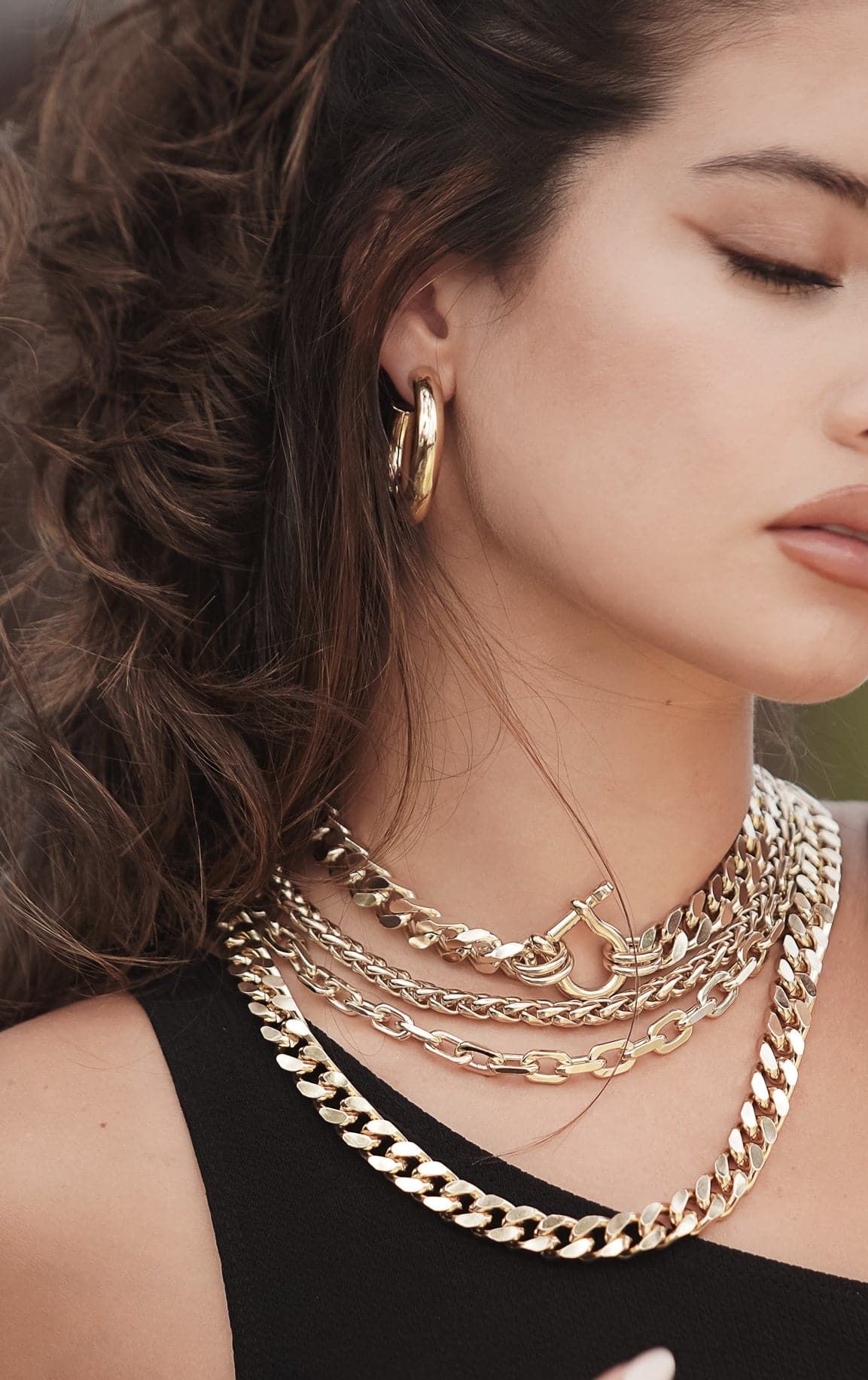 Woman wearing elegant gold jewelry showcasing the Esmé Necklace in this stylish shot