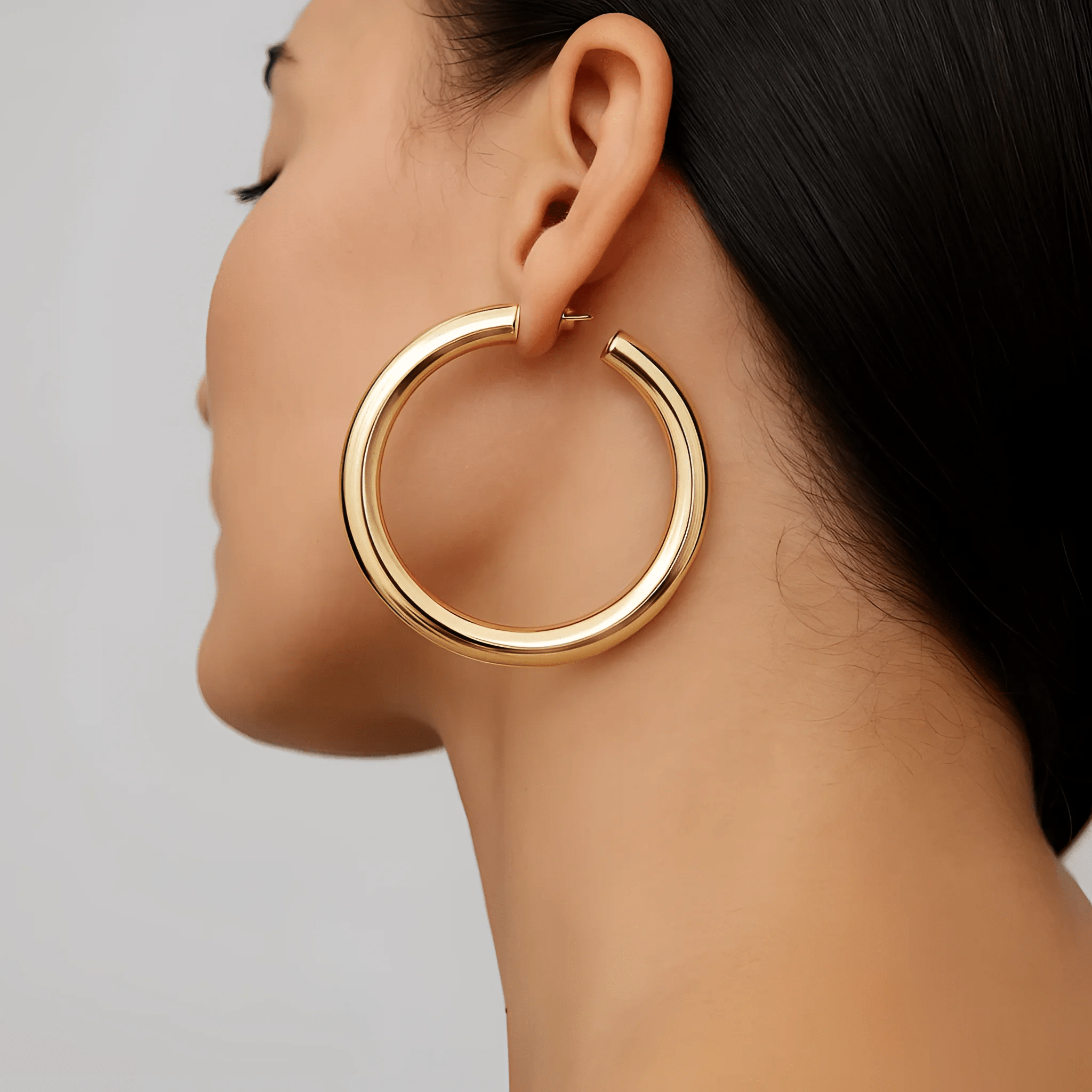 Woman wearing a single 2-inch gold Kelly Hoops earring showcasing elegant jewelry style