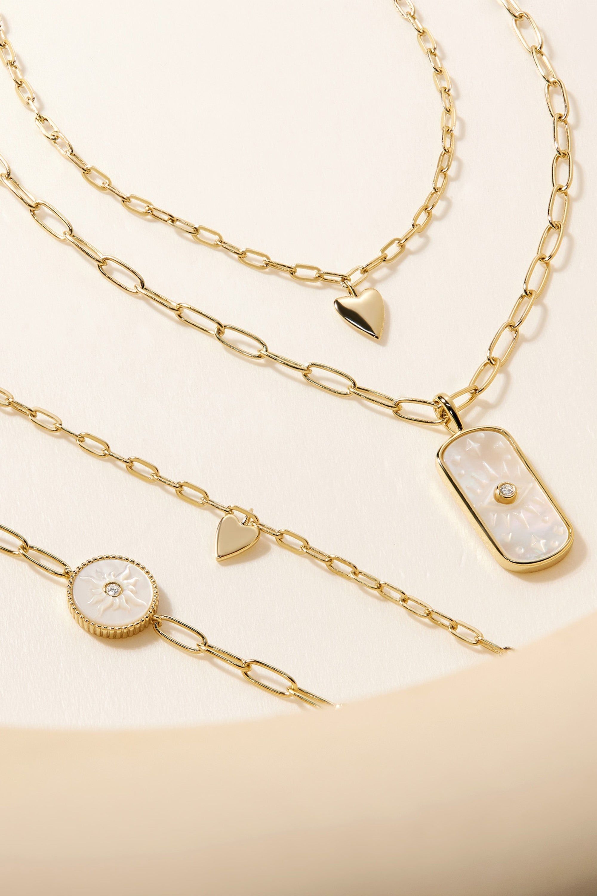 Gold-colored chain necklaces and bracelets with mother-of-pearl and heart charms