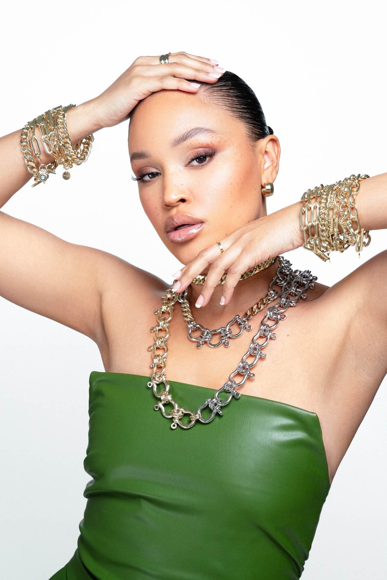 Woman in green top wearing the stylish Triple Gisele Toggle Bracelet with gold jewelry