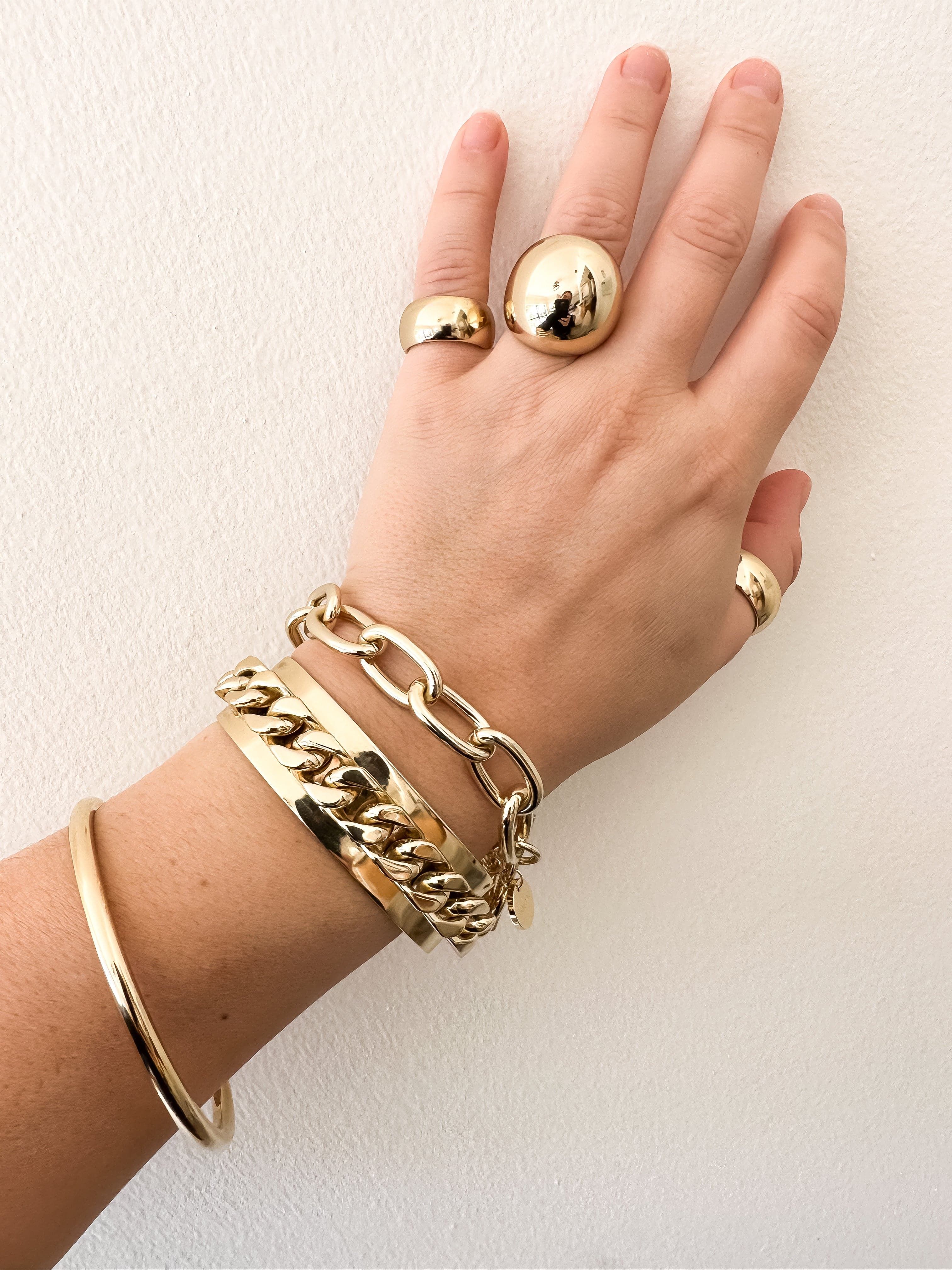 Hand wearing gold rings and bracelets showcasing XL Domed Ring jewelry