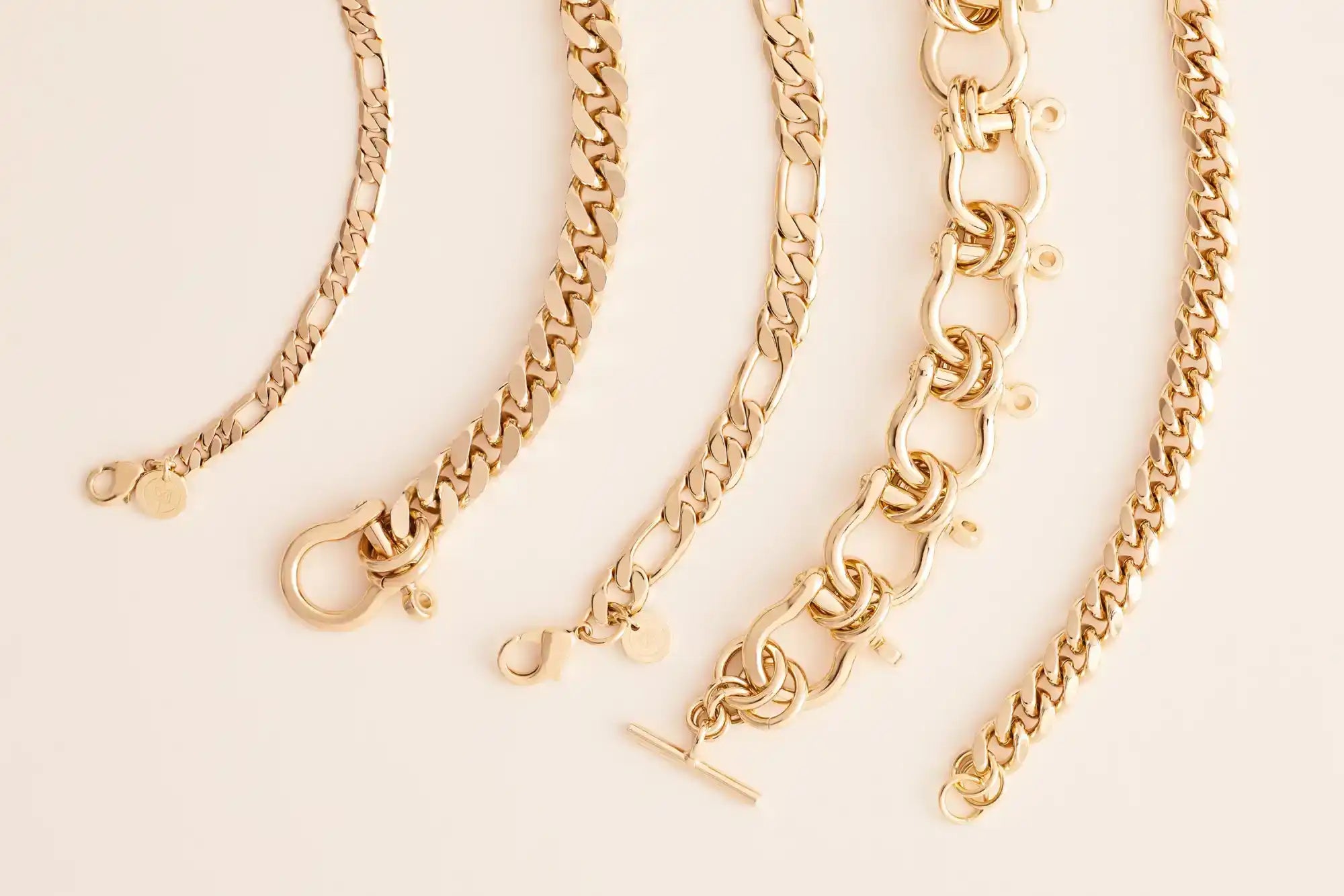A collection of five gold-colored chain bracelets with various link styles and clasps.