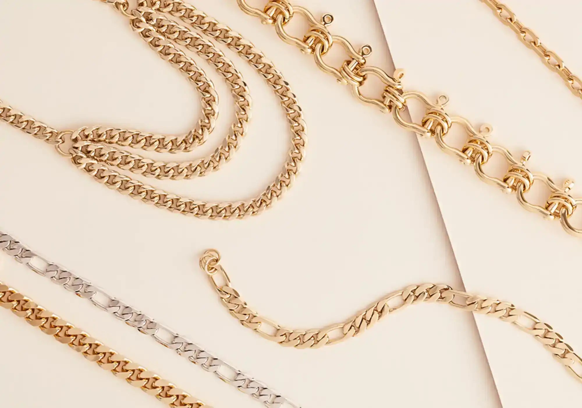 A collection of gold and silver-toned metal chain necklaces and bracelets in various link styles.