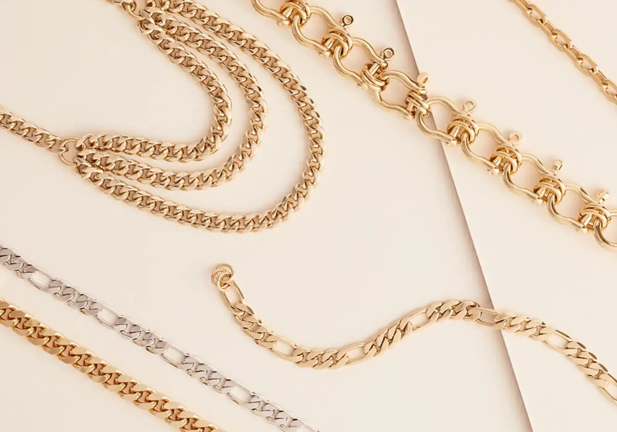 A collection of gold and silver-toned metal chain necklaces and bracelets in various link styles.