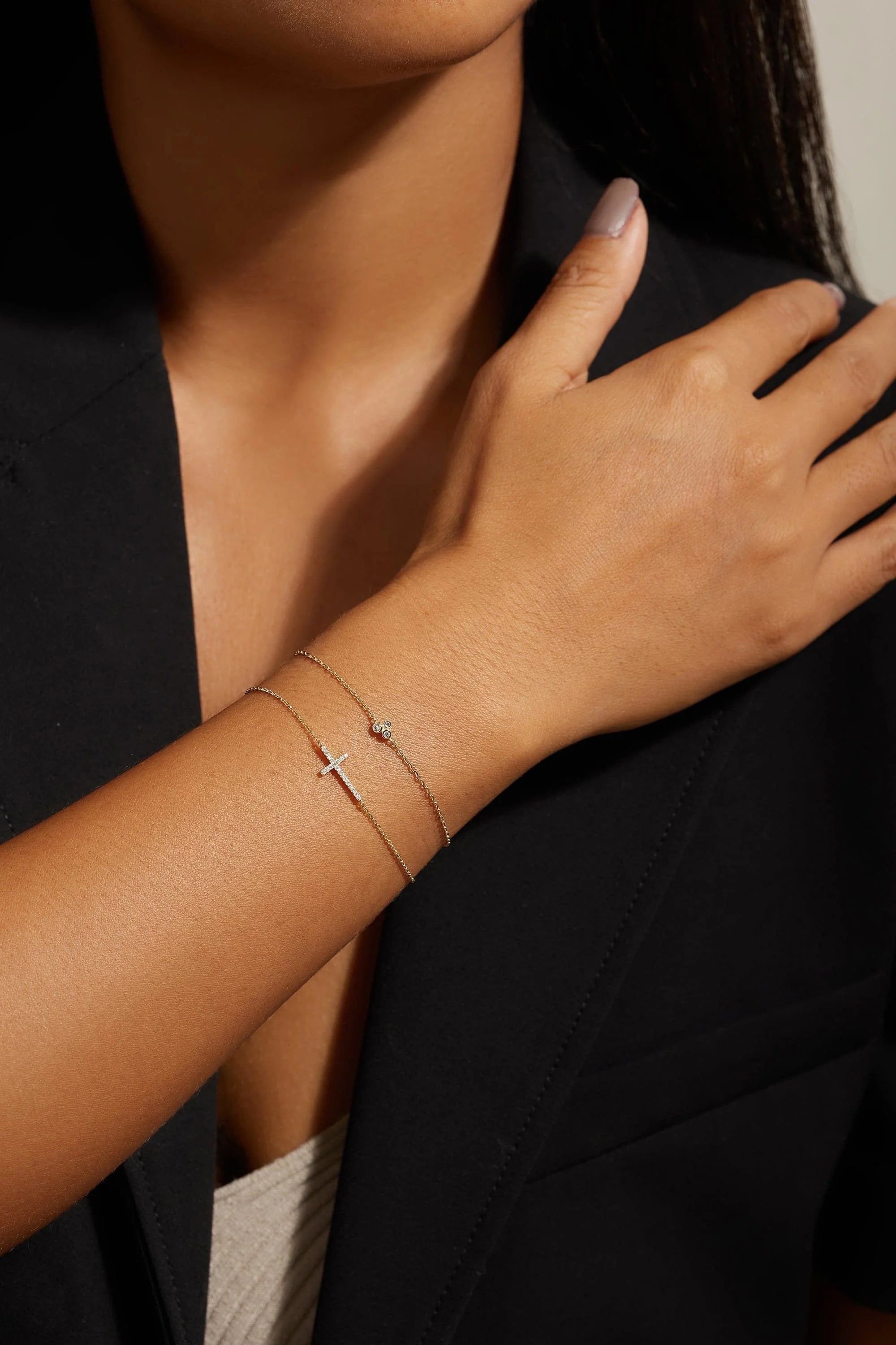 Woman’s arm with delicate gold bracelets showcasing the Horizontal CZ Cross Bracelet