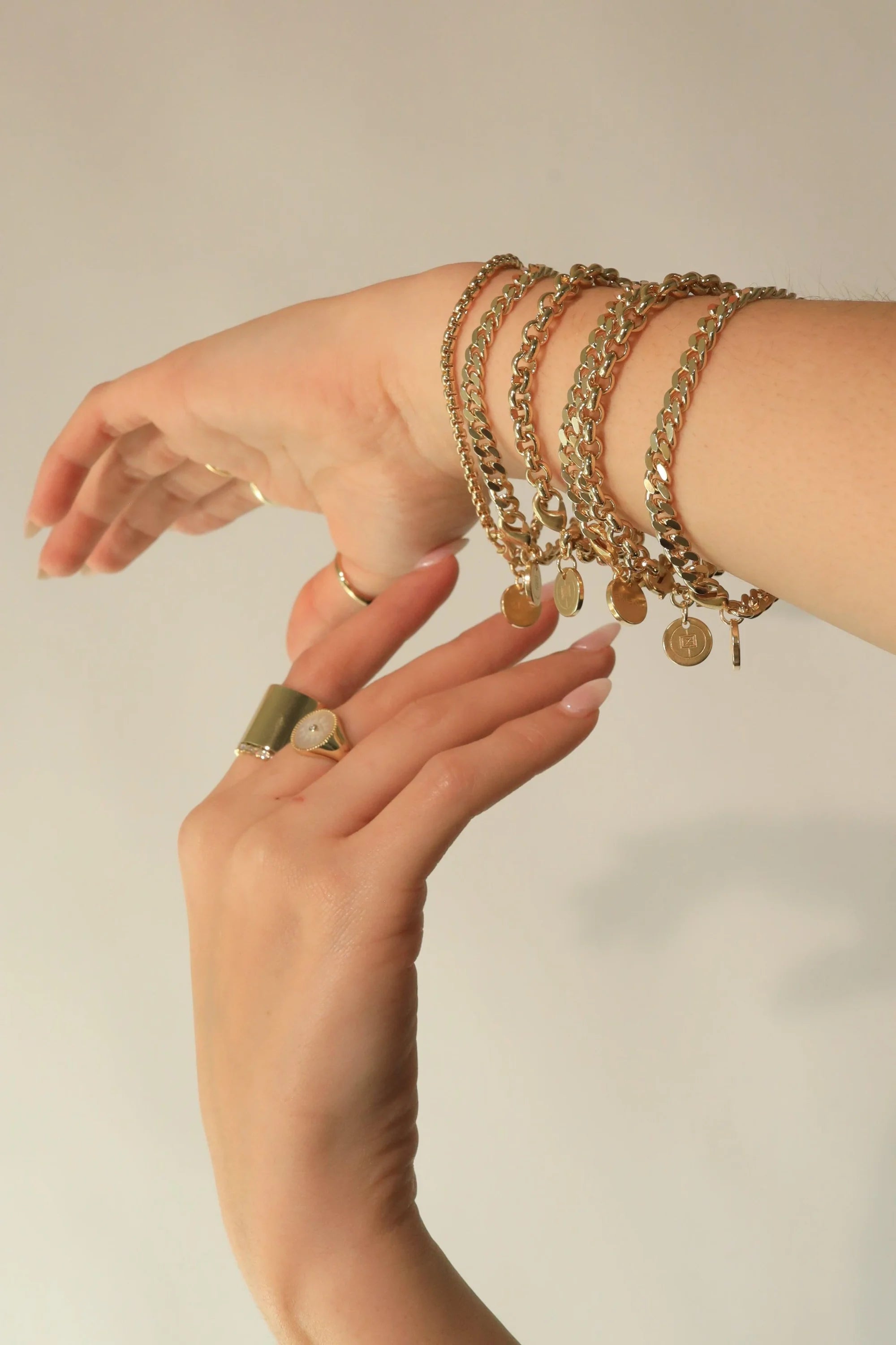 Gold chain bracelets and rings featured in the Micro Link Curb Chain Bracelet product