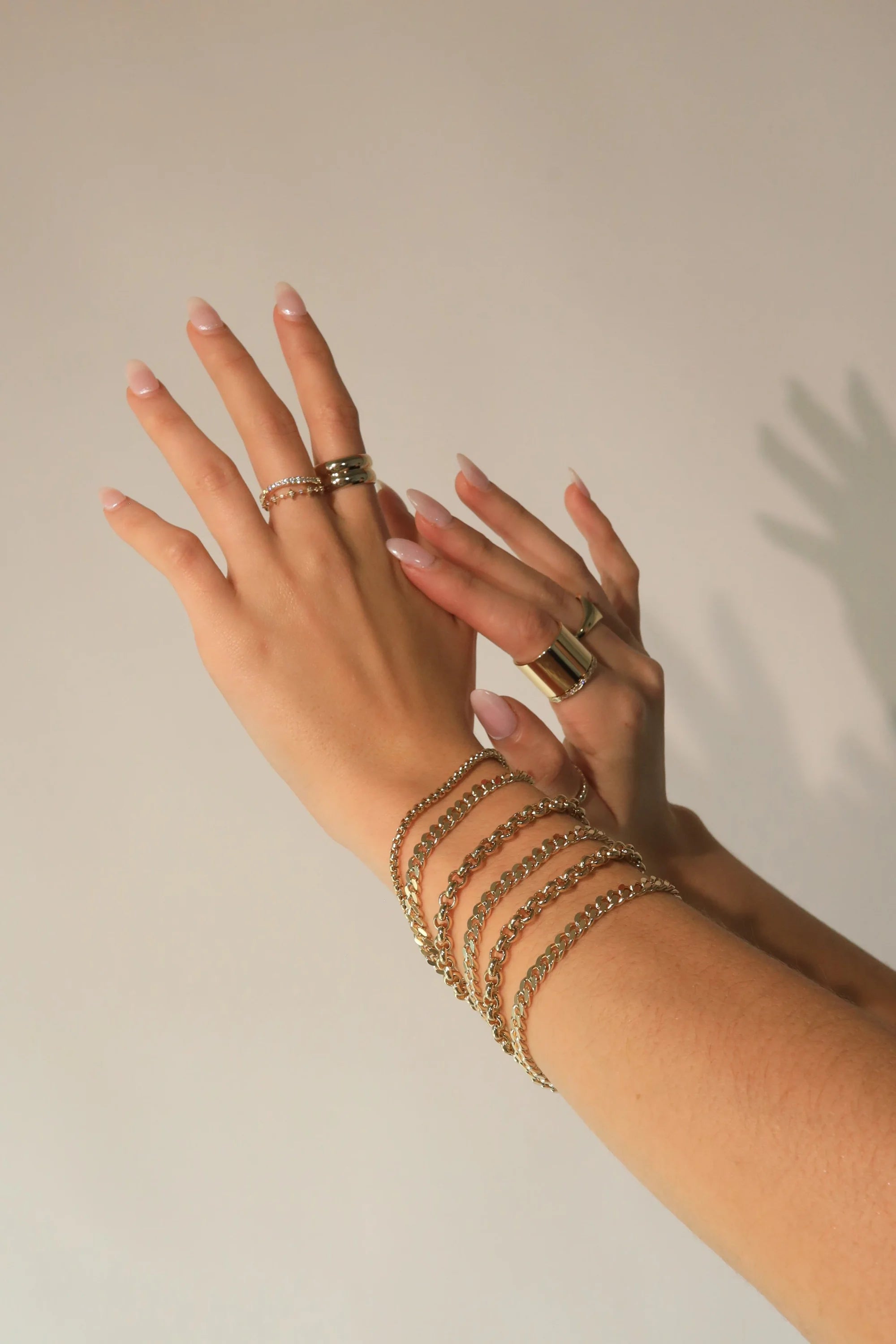 Hands showing off the Micro Royal Rolo Chain Bracelet with gold jewelry highlights