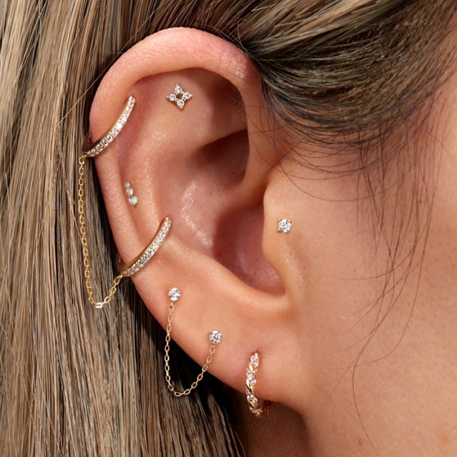 Ear with multiple gold and diamond piercings wearing 14K Gold & Diamond Twisted Huggie Hoops