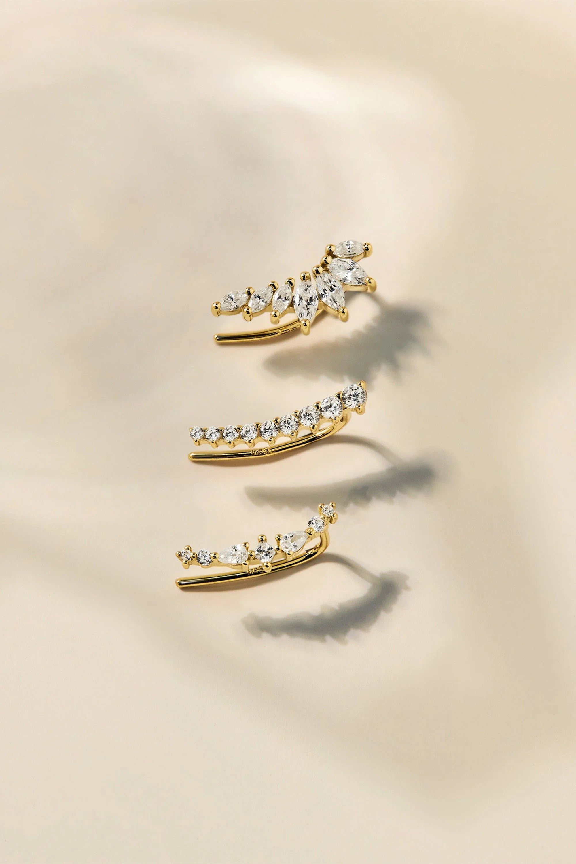 Three gold ear climbers with clear gemstones from the Graduated CZ Bar Ear Crawl shown
