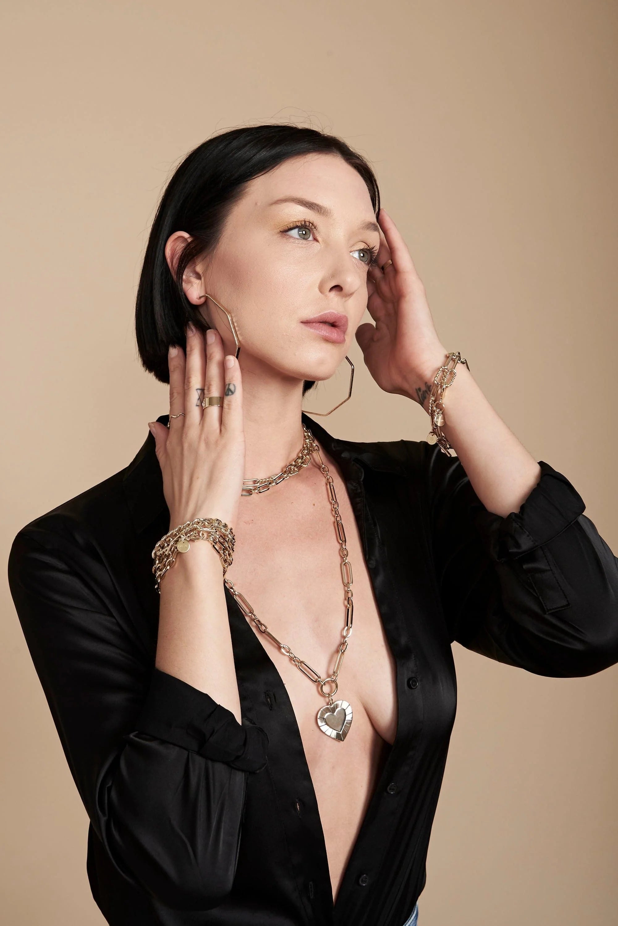 Woman wearing gold jewelry with a large multi link chain and heart pendant necklace