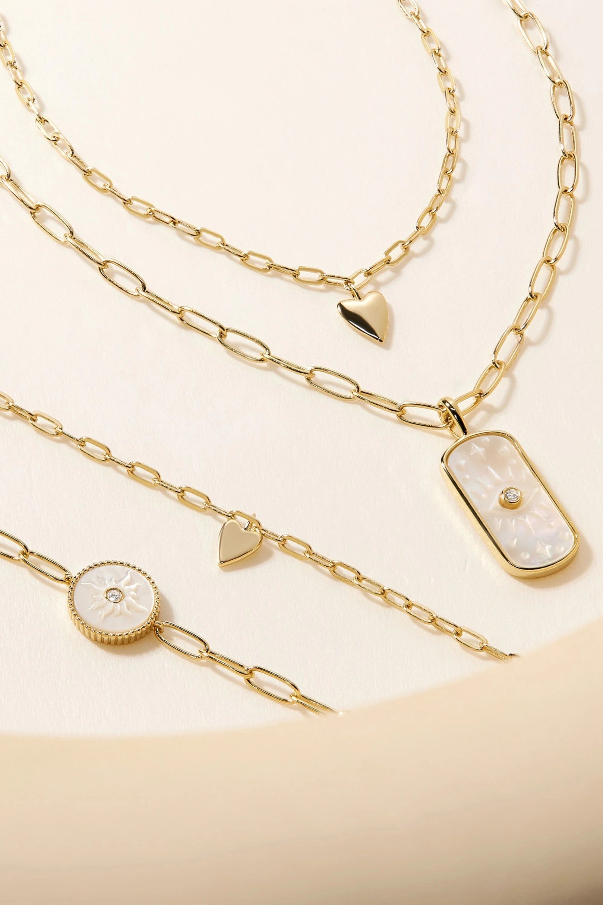 Gold-colored chain necklaces and bracelets with mother-of-pearl and heart charms