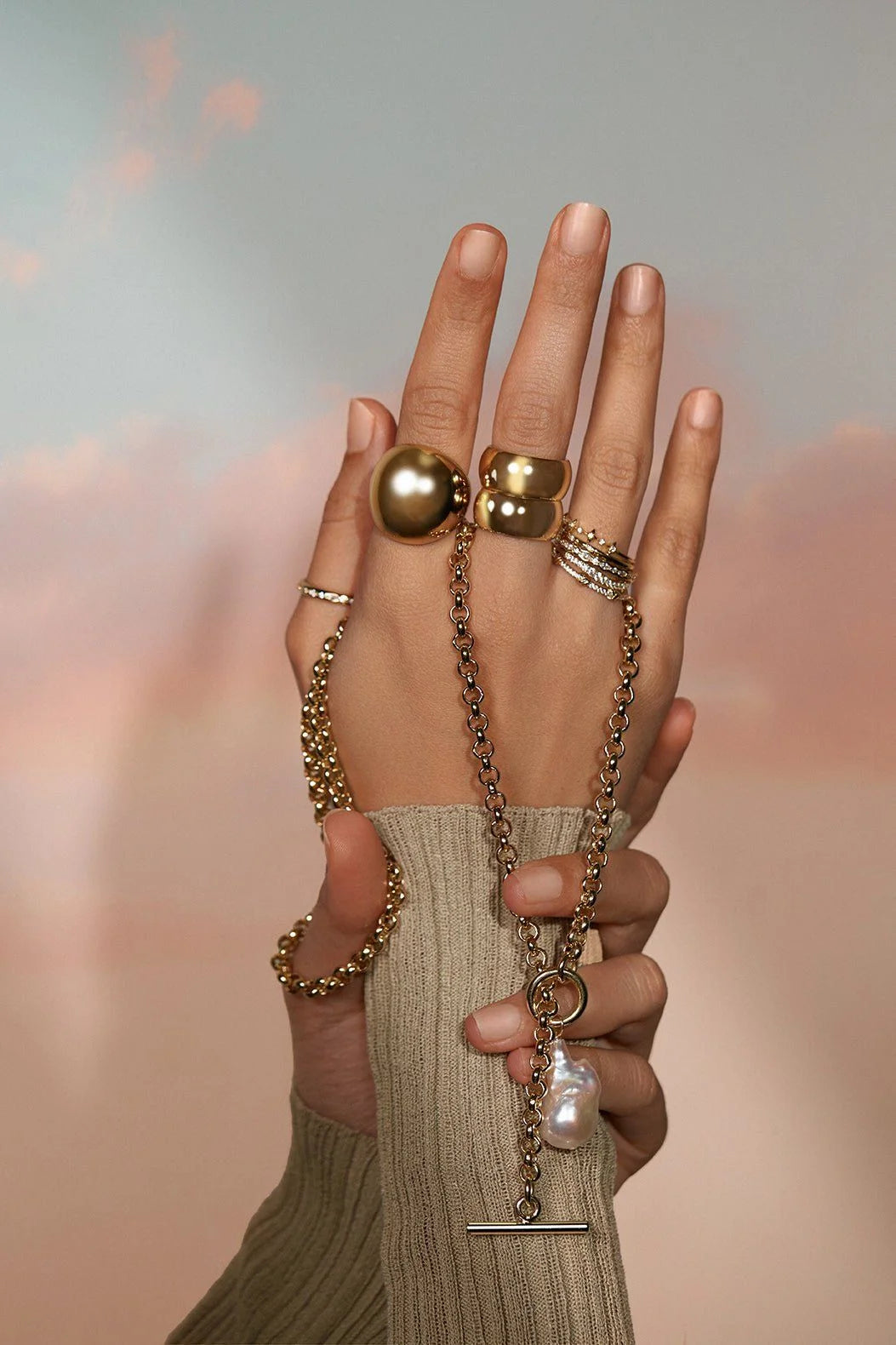 Close-up of hands with gold rings and a pearl necklace for Twinkle CZ Ring product