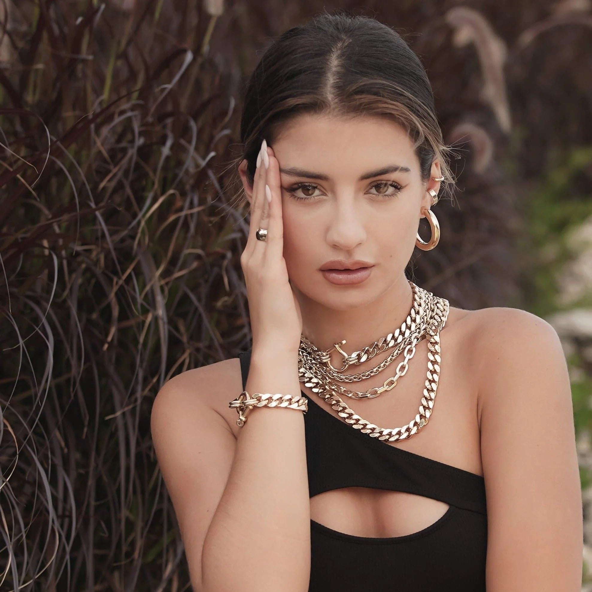 Woman wearing gold jewelry featuring the Lennon Necklace in a stylish setting
