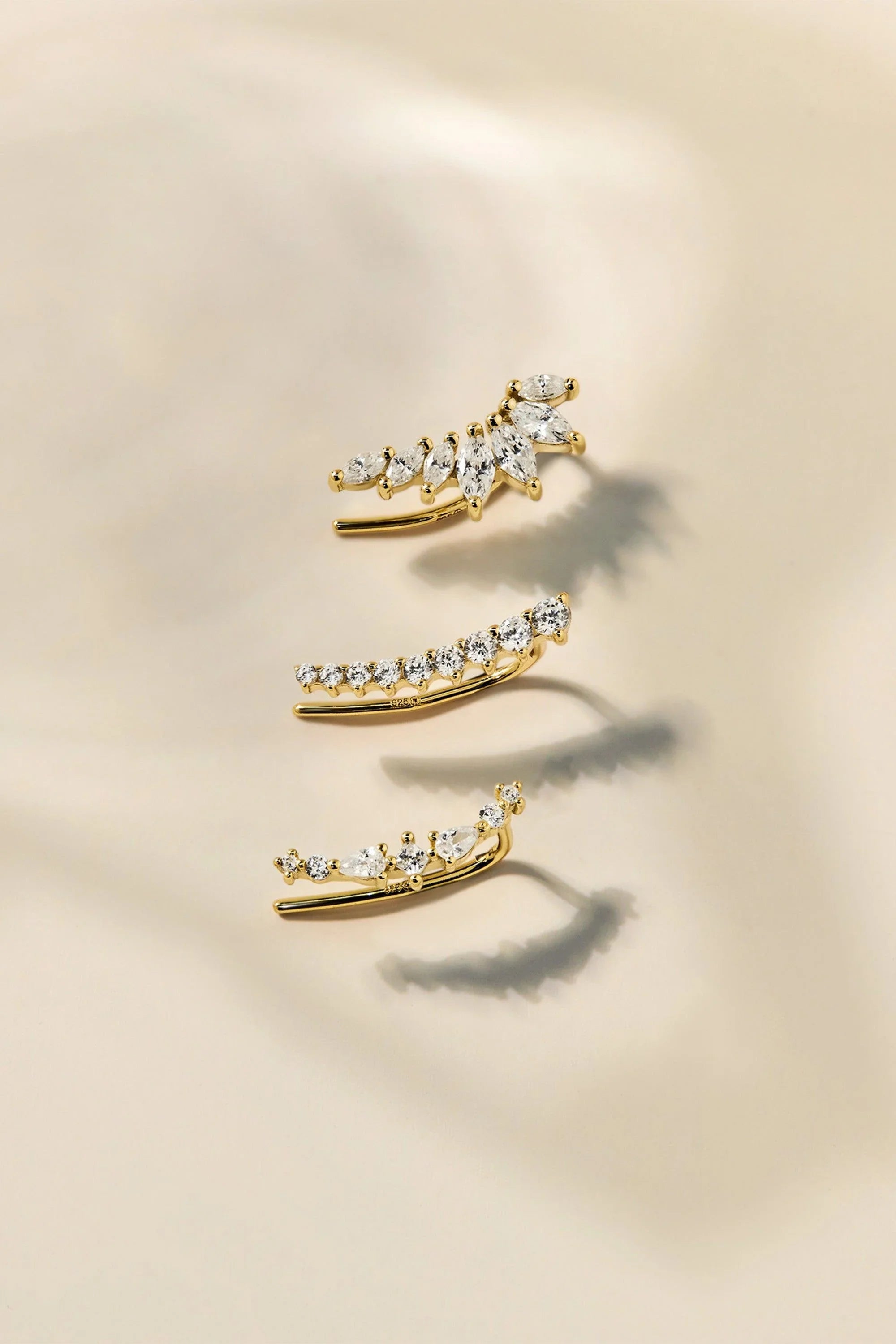 Three gold ear climbers with clear gemstones from the Graduated CZ Bar Ear Crawl shown