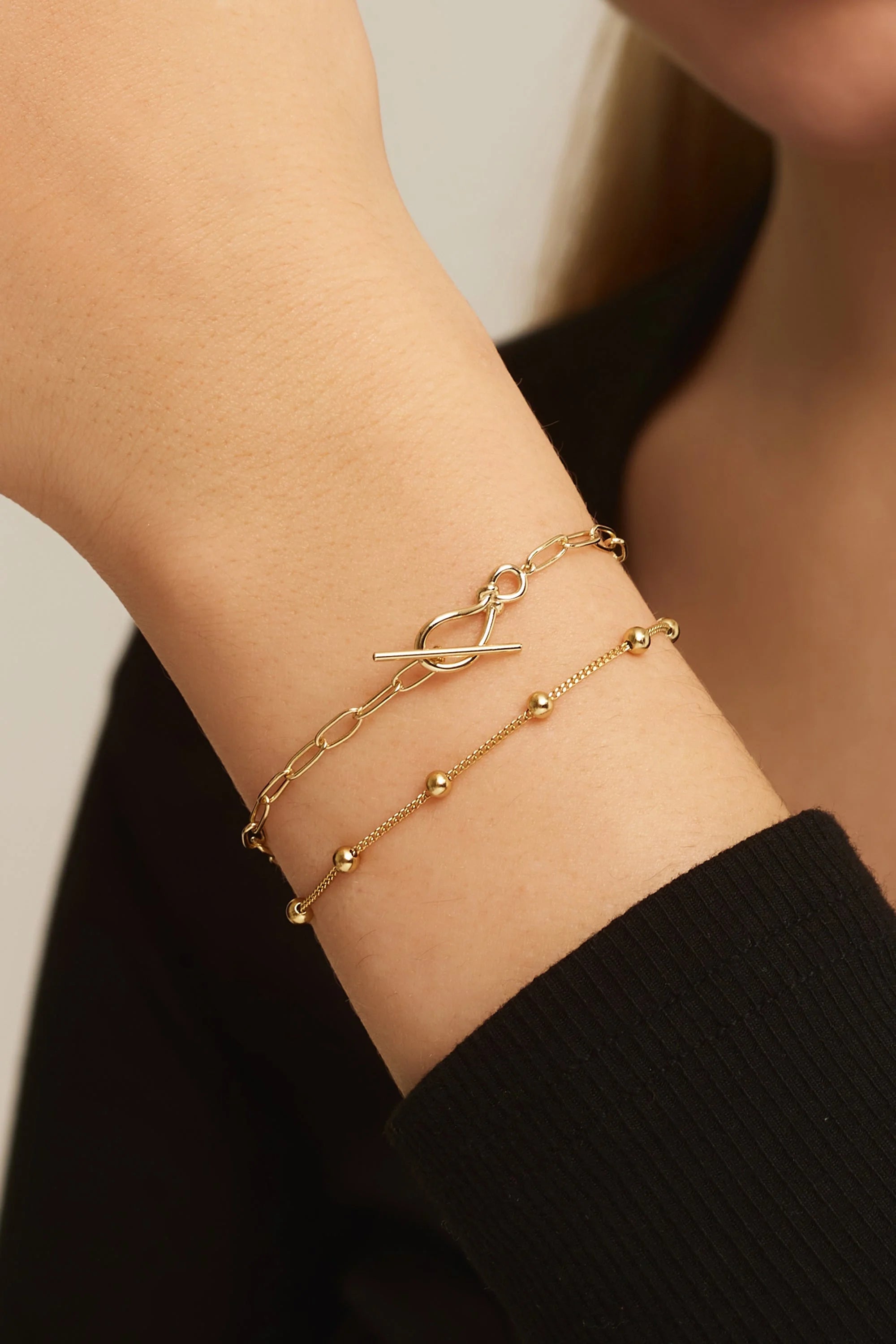 Gold-toned layered paperclip chain bracelet with knot toggle clasp in sterling silver style