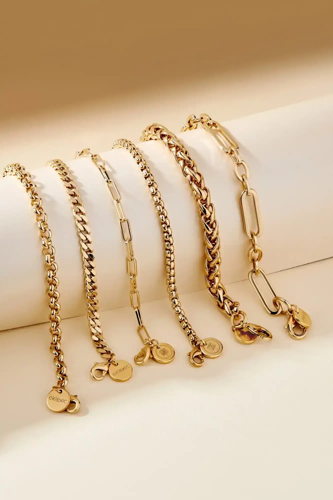 Six golden chain bracelets with charms.