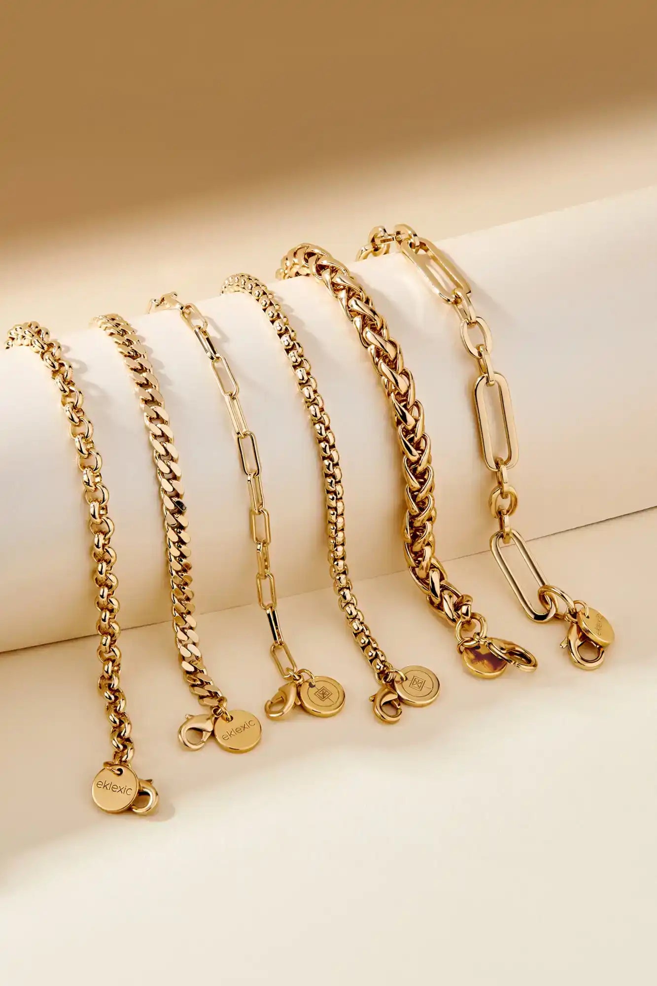 Set of gold chain necklaces on a beige surface