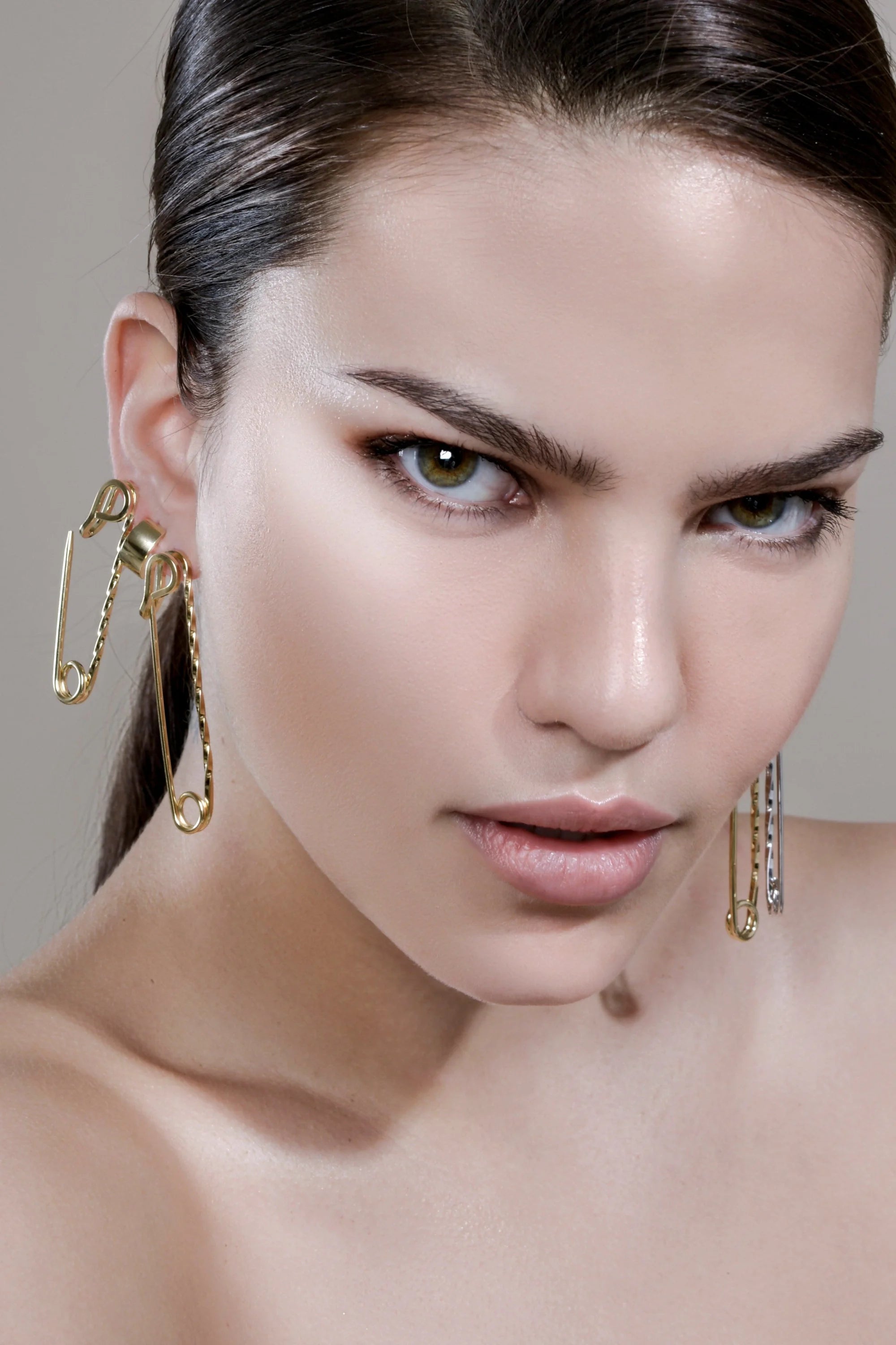 Woman wearing small twisted safety pin earrings in 14k yellow gold with yellow gold rhodium