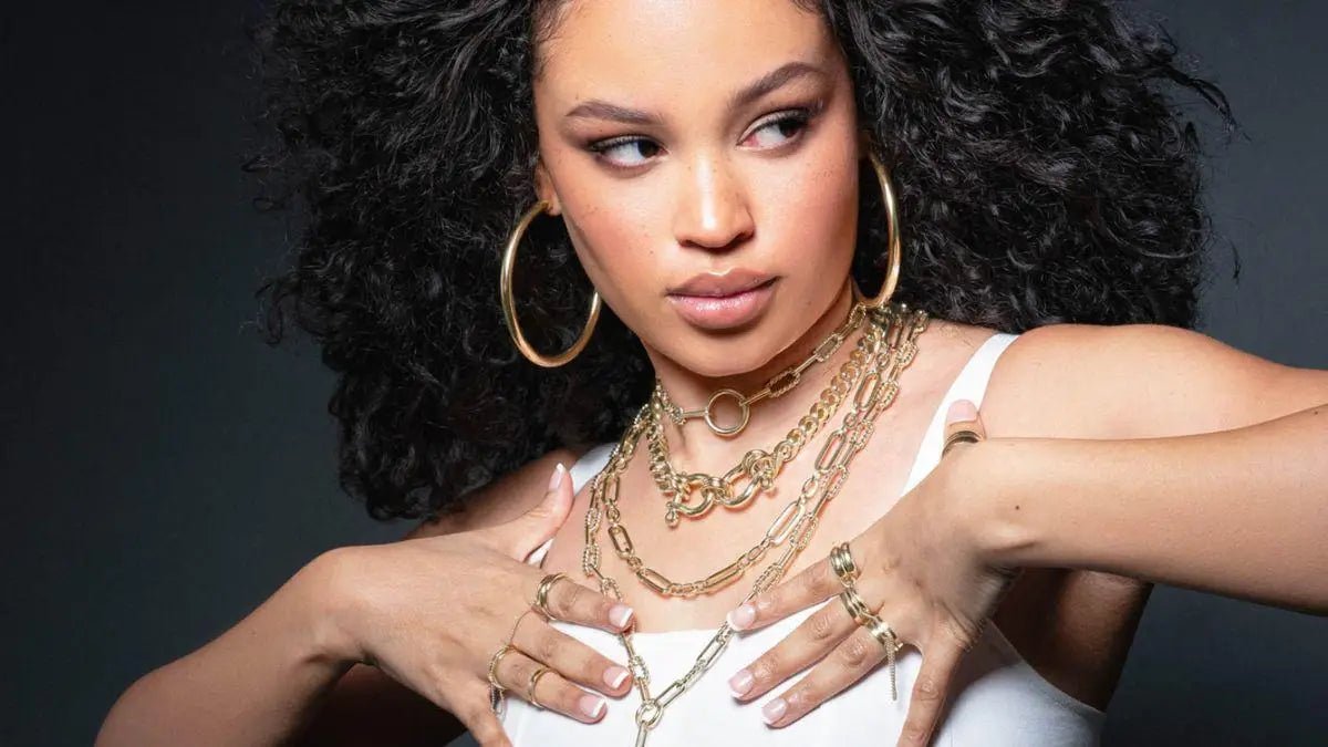 Woman with dark curly hair wearing gold chain necklaces and rings in Best Sellers collection