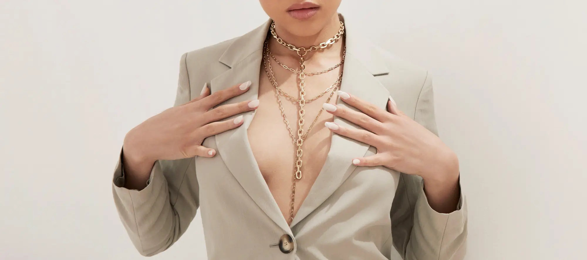 Woman in a beige blazer wearing layered gold necklaces from LARIAT NECKLACES collection