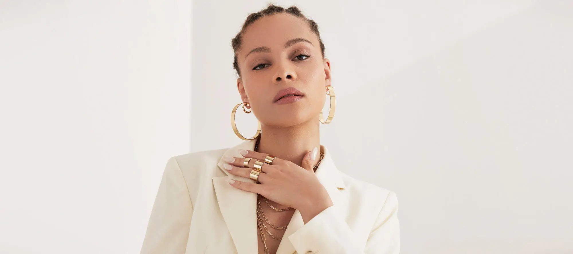 Woman in a white blazer showcasing Skylar Hoops color with elegant gold jewelry.