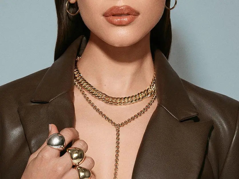 Woman in brown leather jacket showcasing gold link chain necklace color.