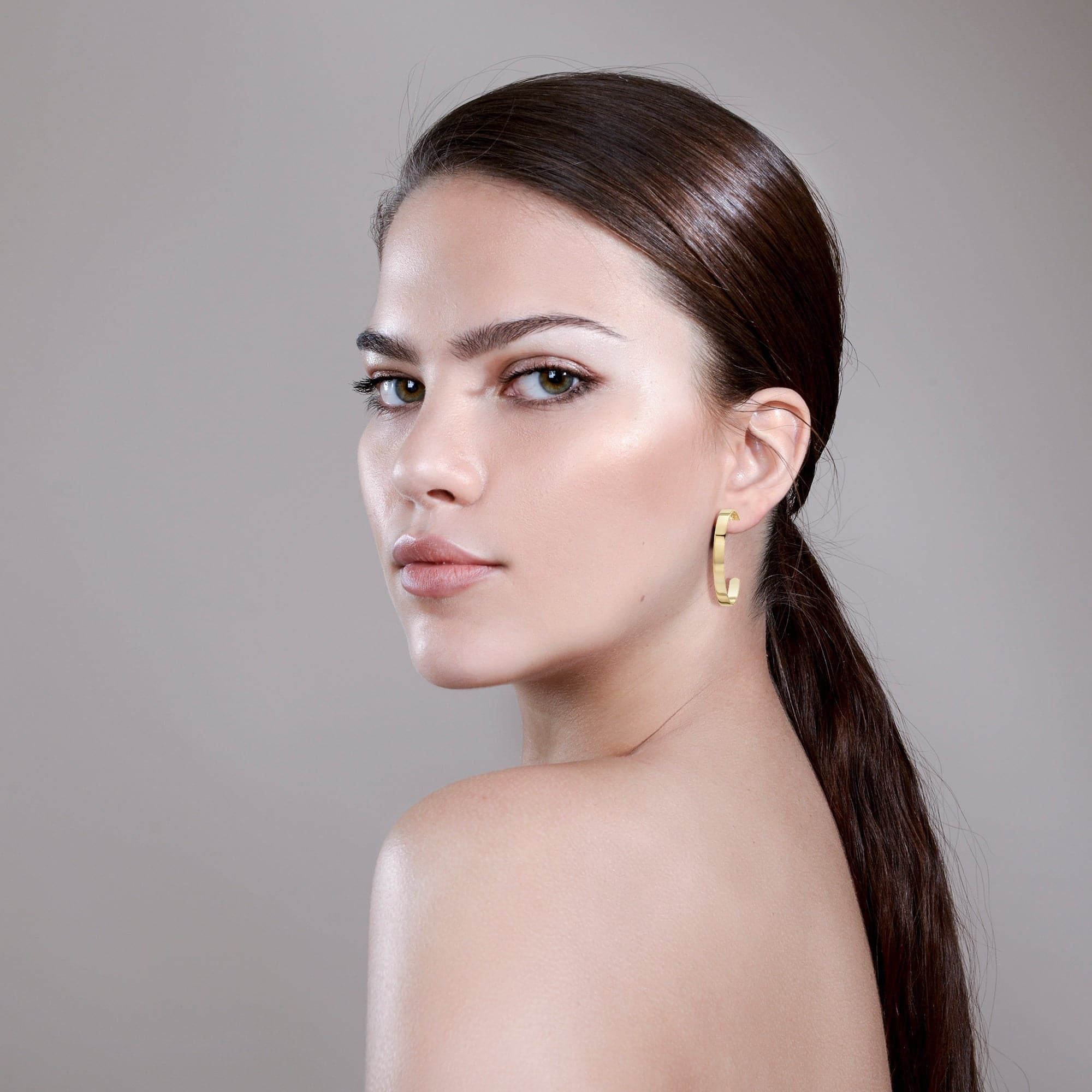 Woman showcasing sleek hair and 1.5’’ Isla Hoops made of recycled brass