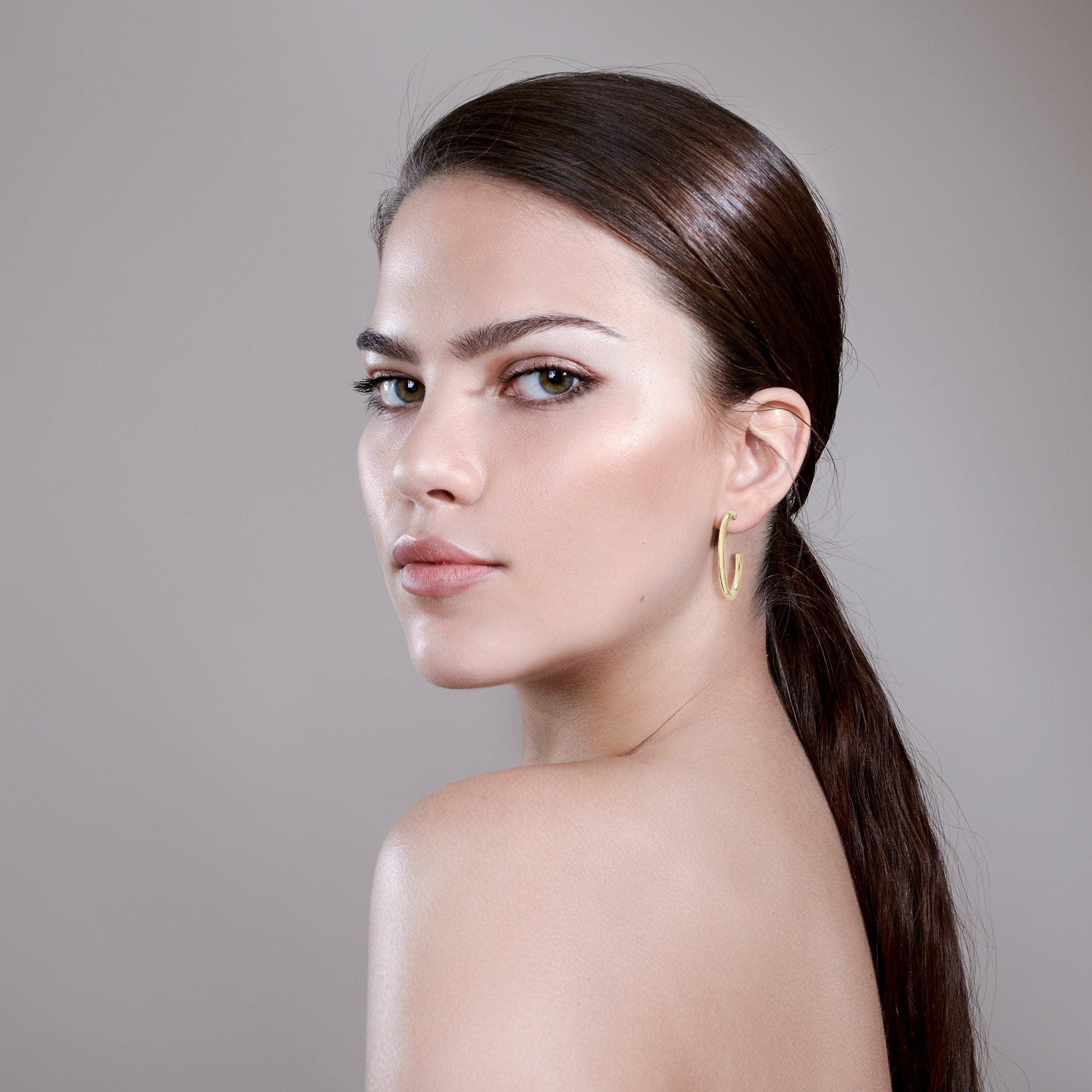 Woman showcasing sleek ponytail and Ultimate Hoops in recycled brass wire, yellow gold