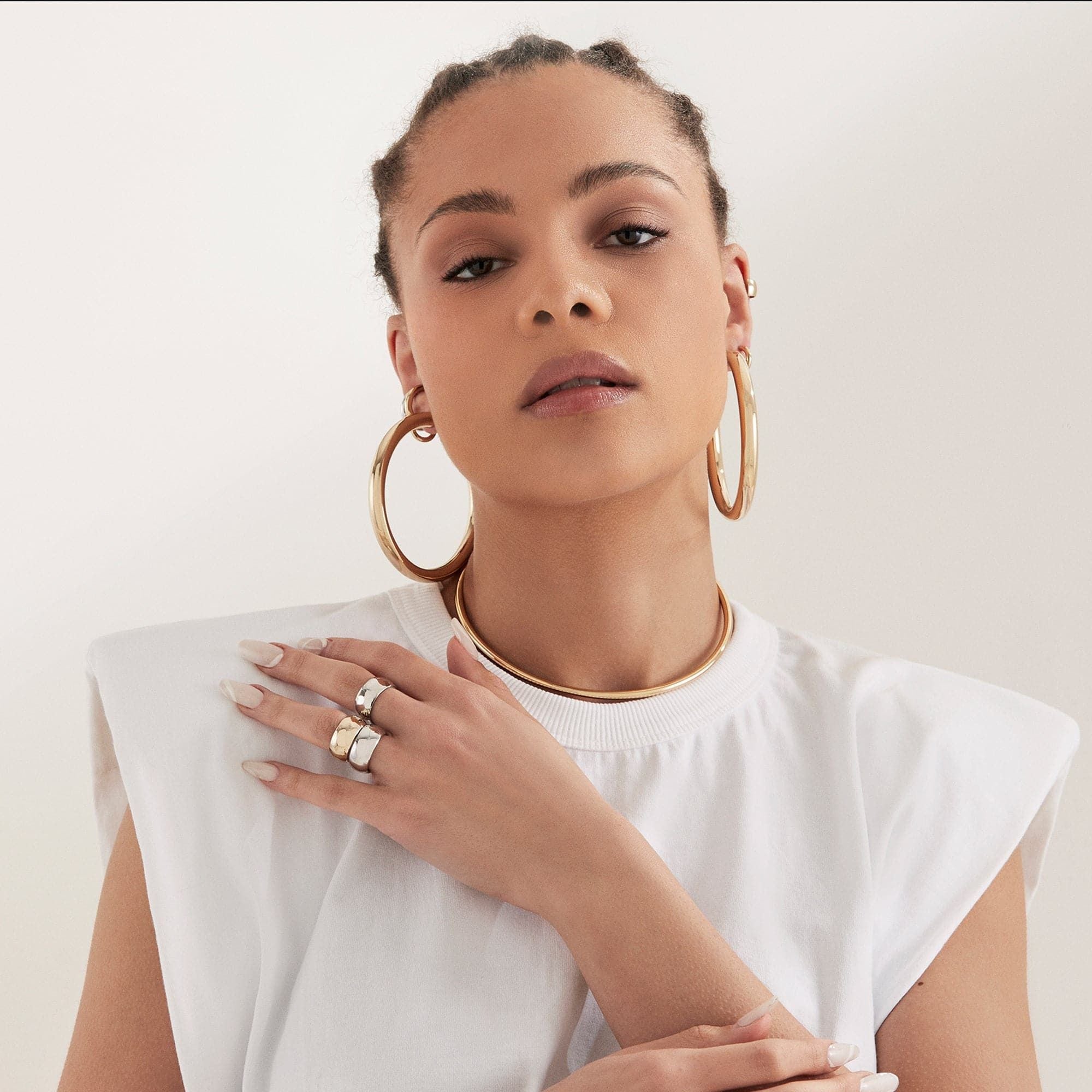 Woman showcasing elegant gold Ryan Hoops jewelry in a stylish setting