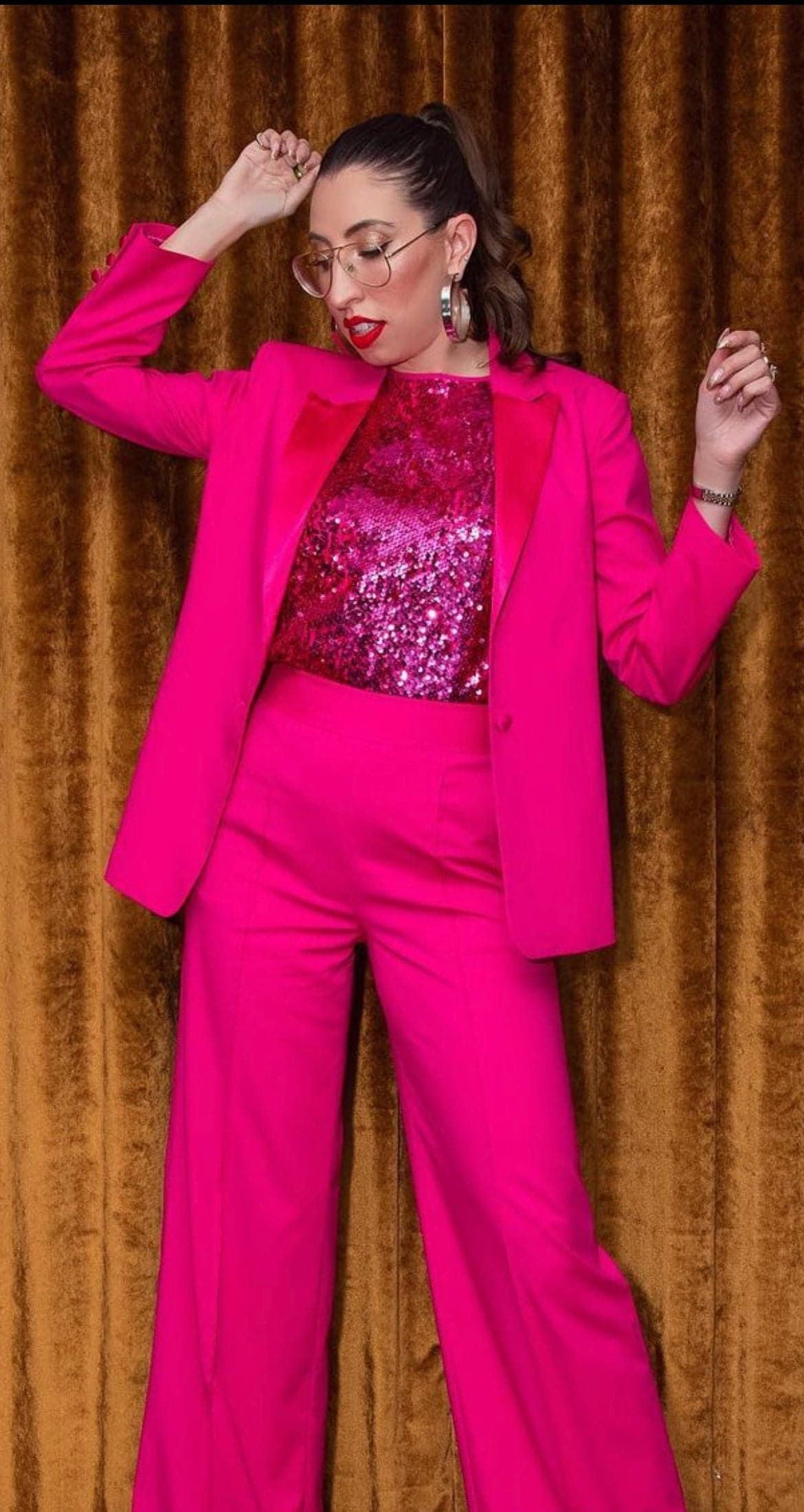 Woman in a bright pink suit wearing wide flat recycled brass Skylar Hoops