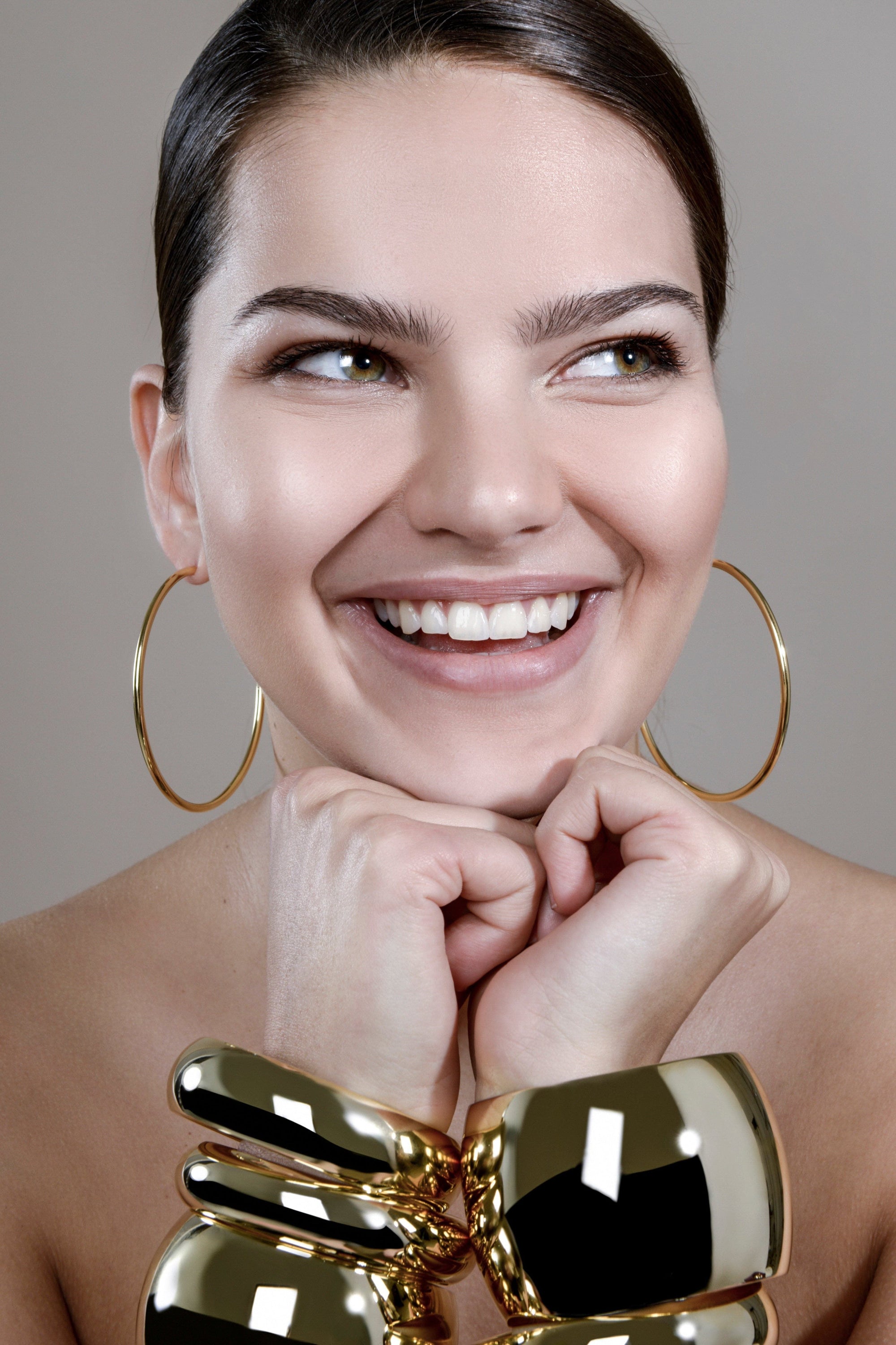 Smiling woman wearing 2.5’’ Ultimate Hoops made with recycled brass wire in yellow gold