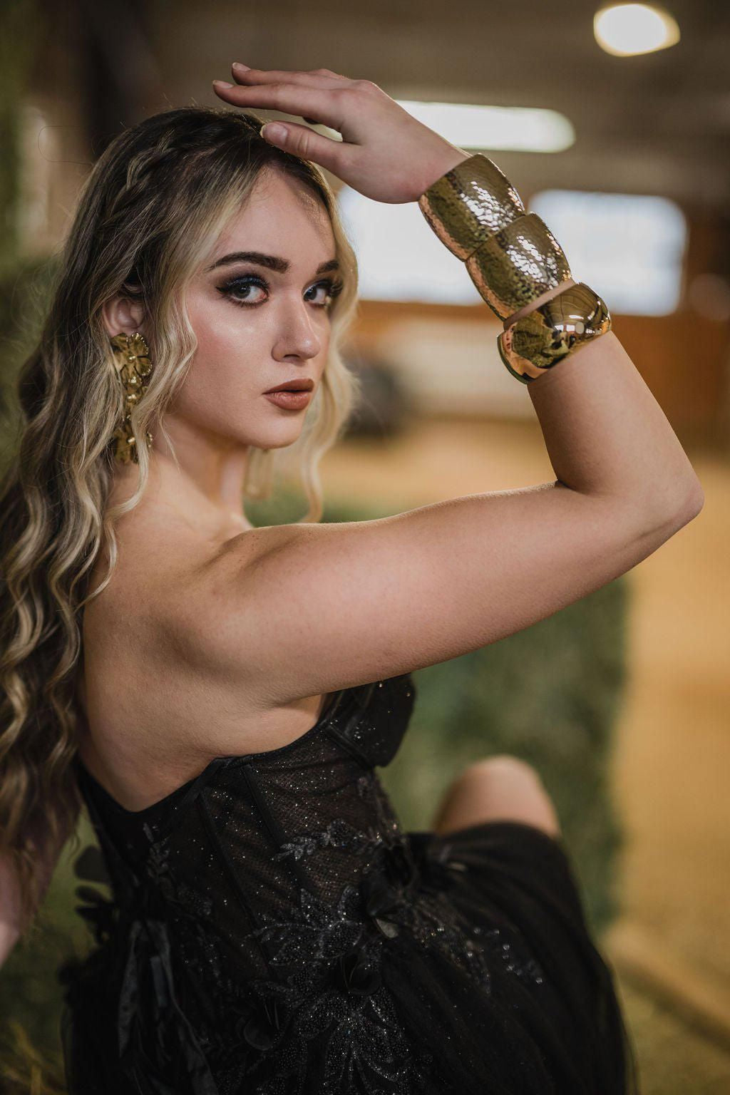 Woman in black dress showcasing 2 Inch wide Recycled Brass Hammered Cuff with gold jewelry