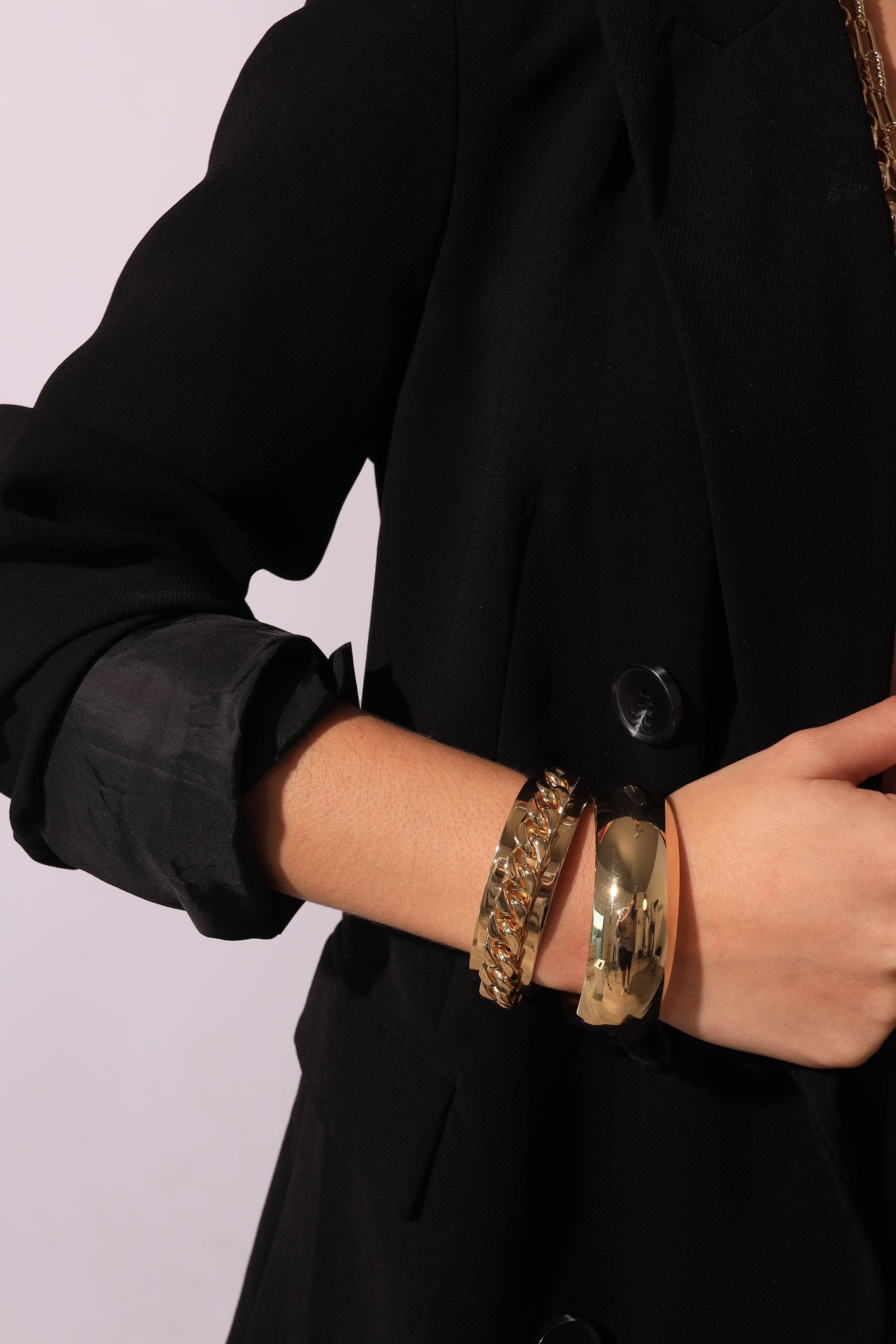 a woman wearing a black coat and two gold bracelets