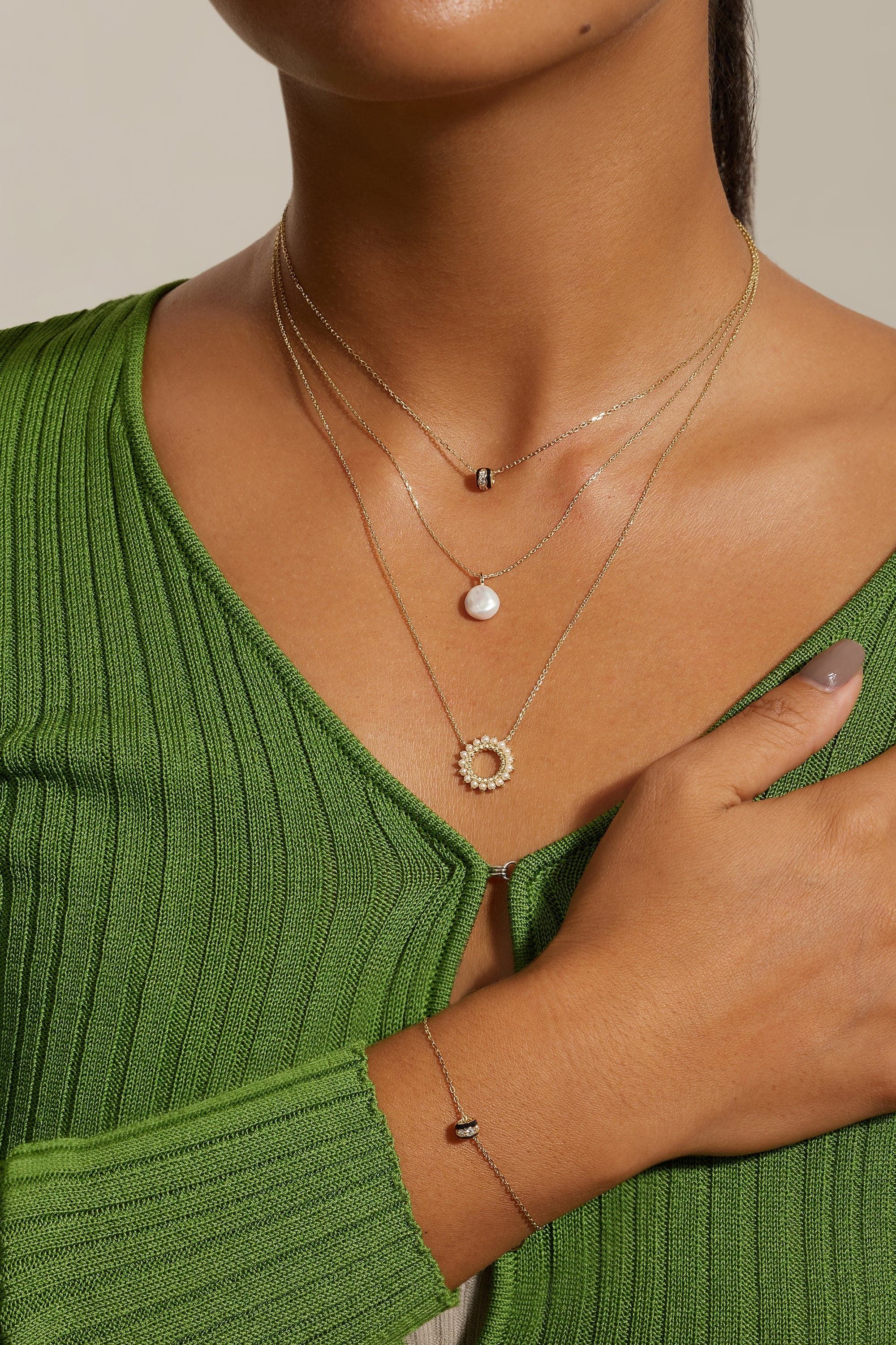 a woman wearing a green sweater and a necklace