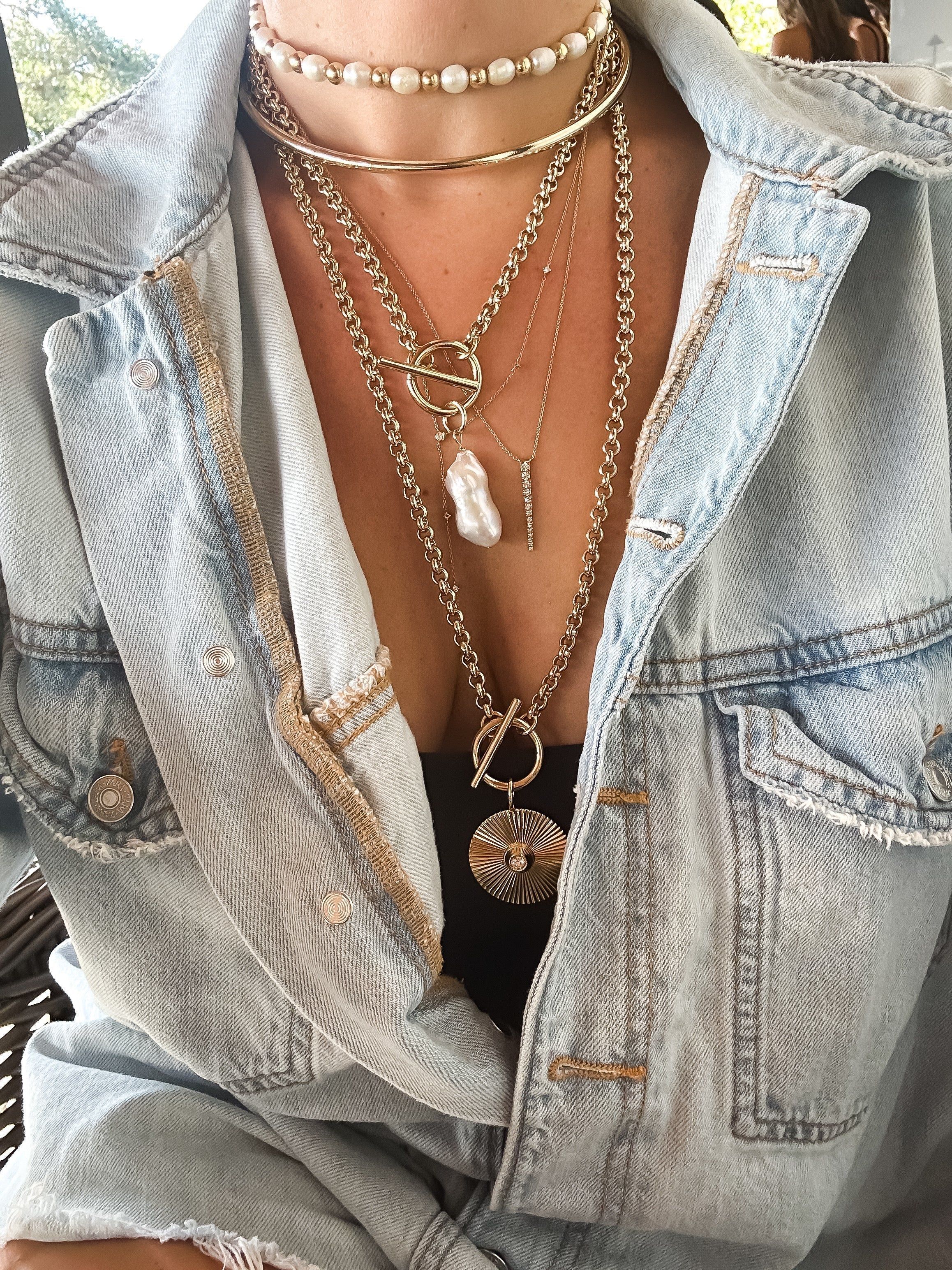 a woman wearing a denim jacket and a necklace