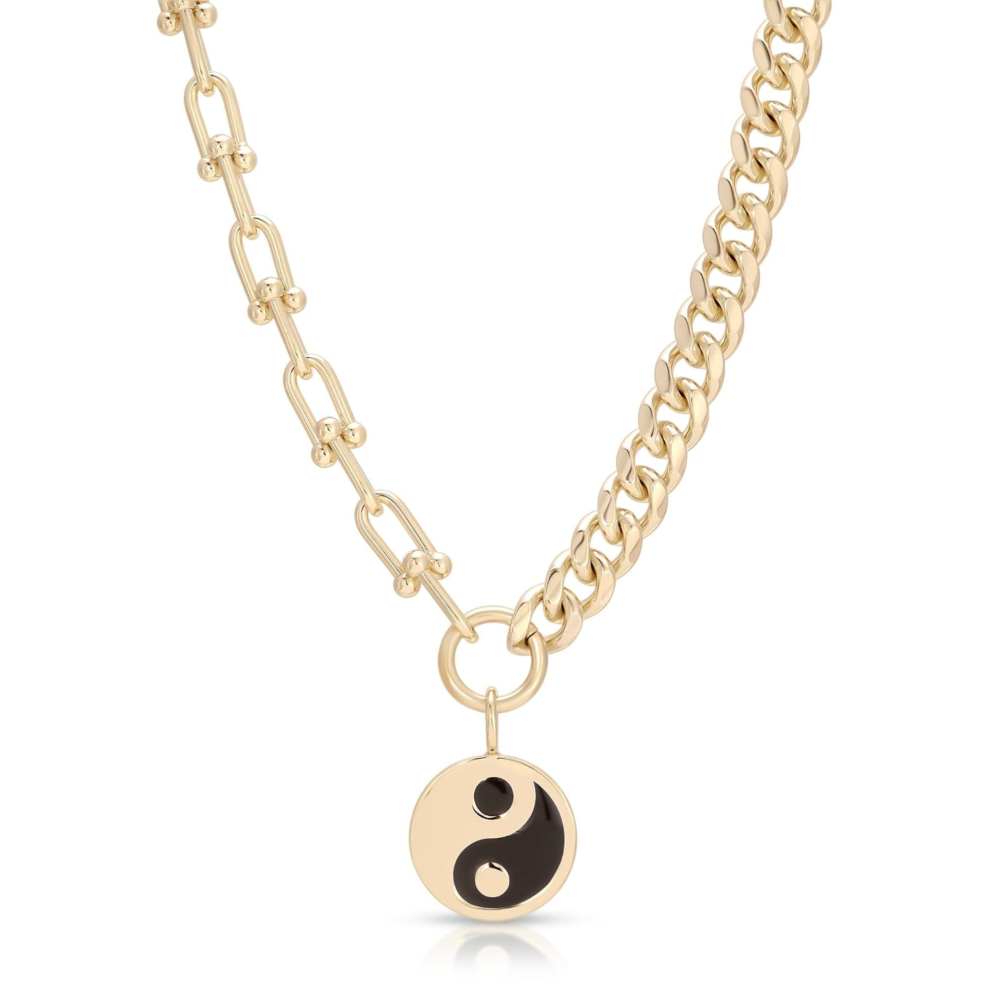 a gold necklace with a black yin symbol on it