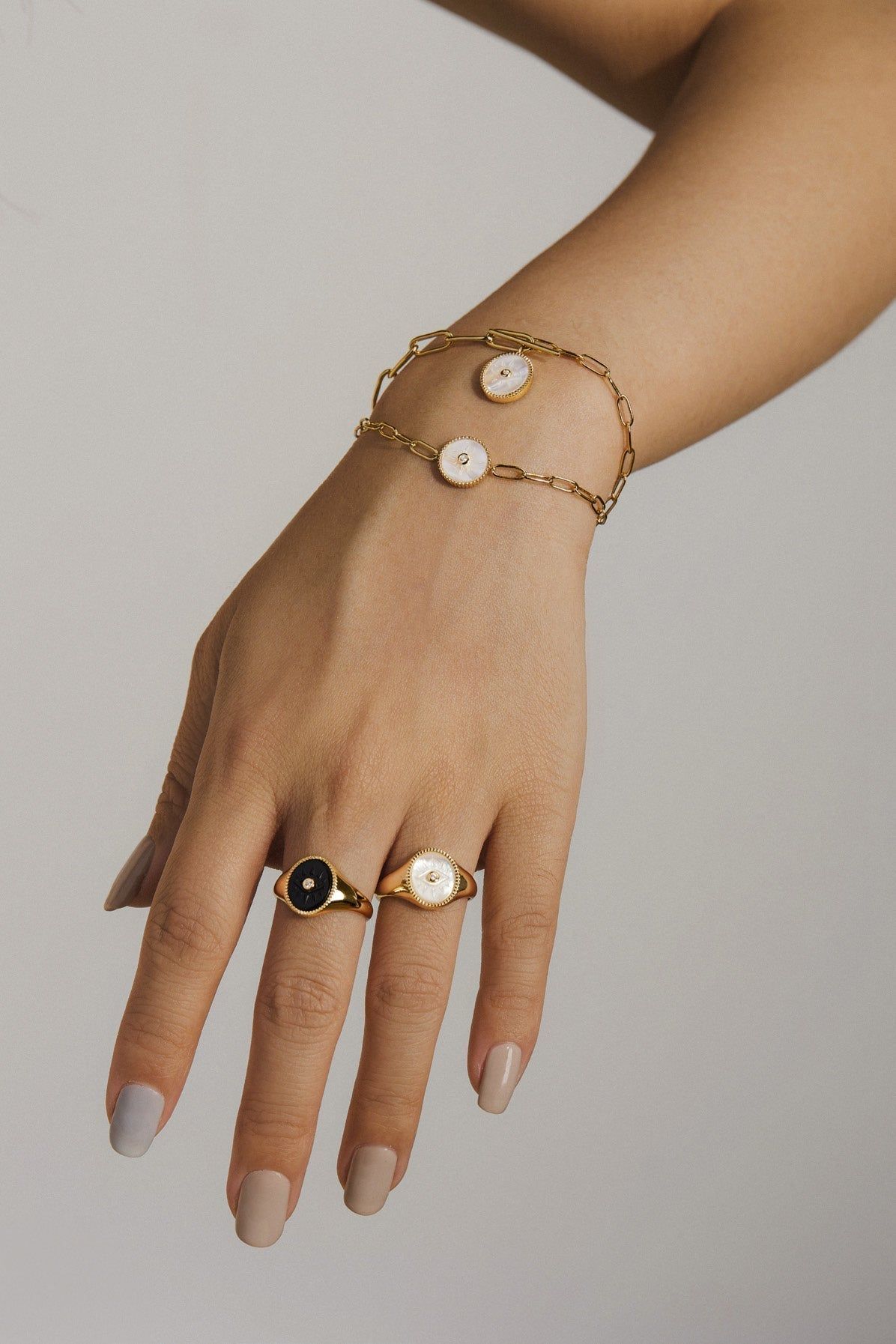 a woman's hand wearing a gold bracelet with pearls