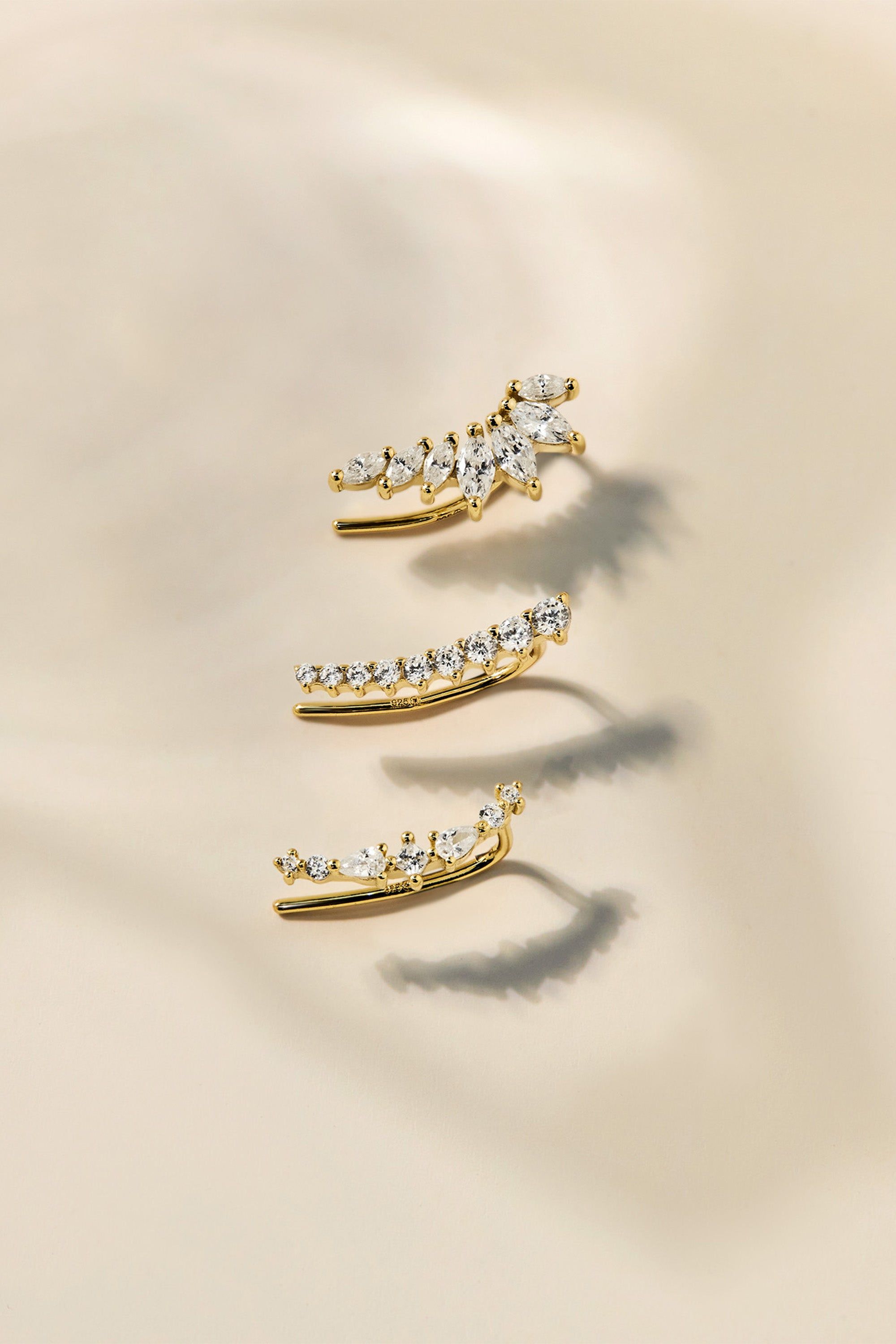 three gold - plated ear clips with clear stones