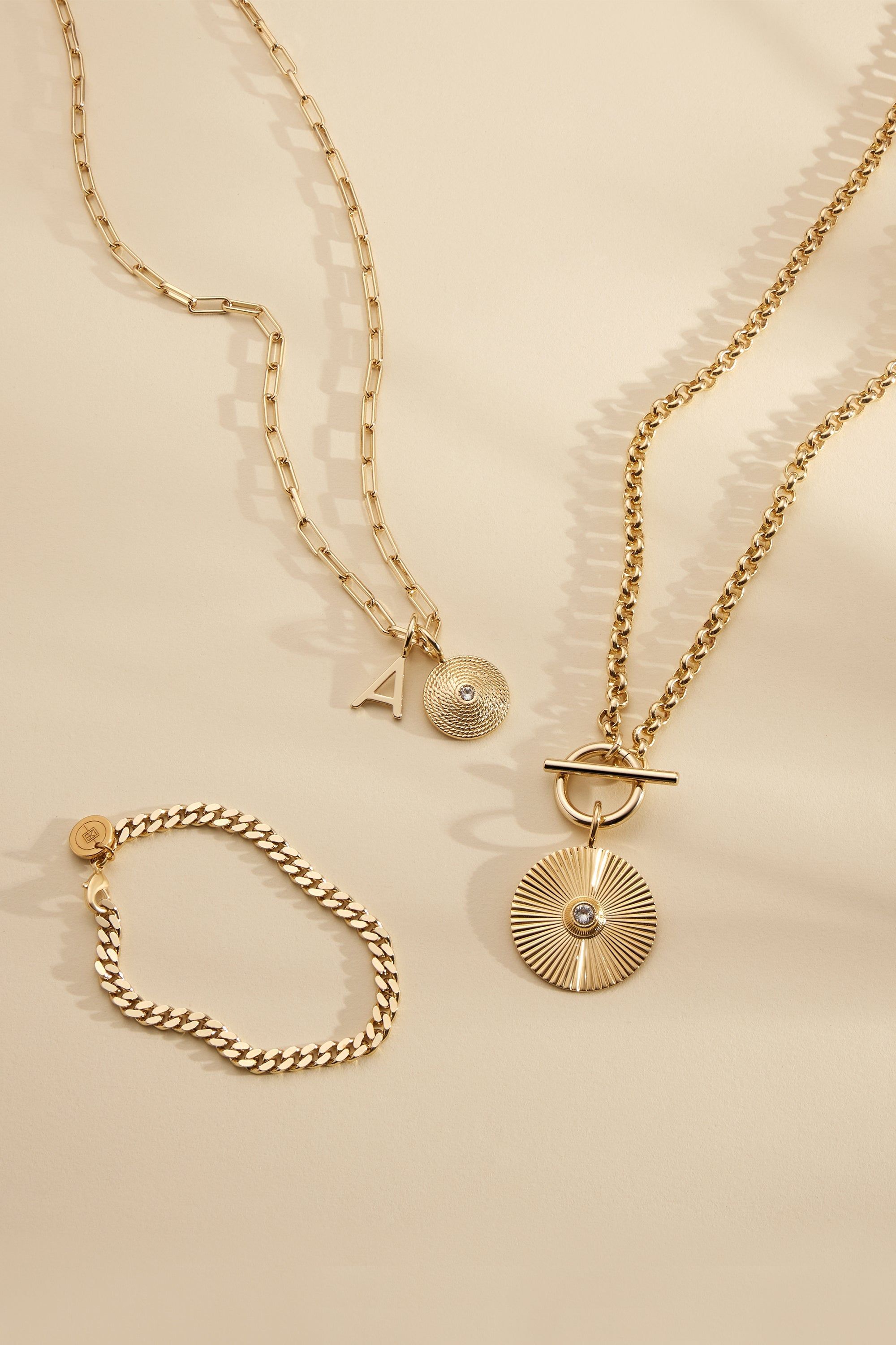 three different necklaces on a white surface