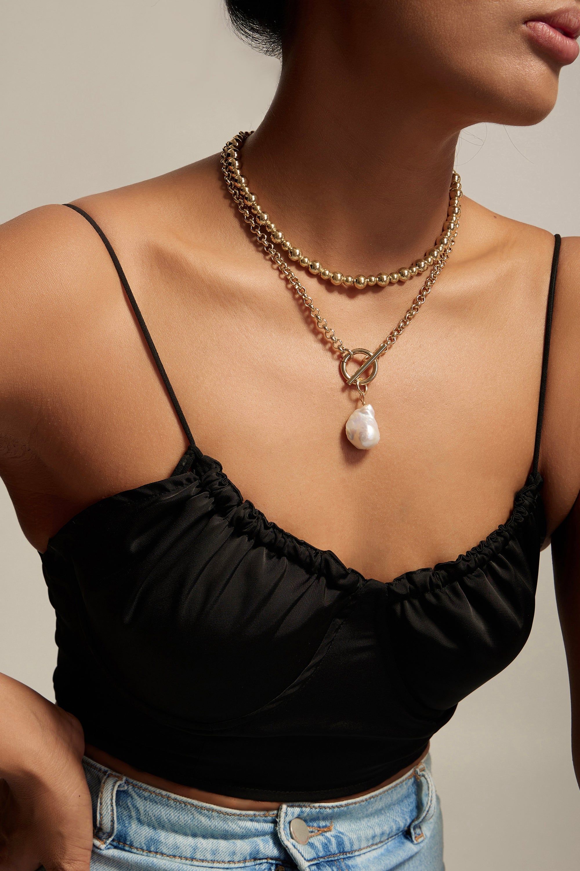 a woman wearing a black top and a pearl necklace