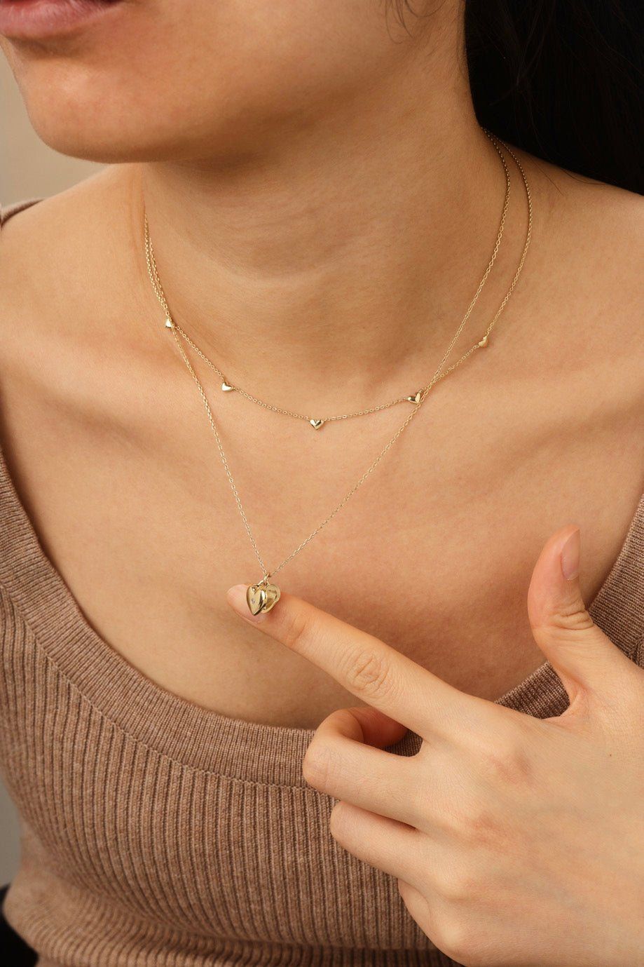 a woman wearing a necklace with a heart on it